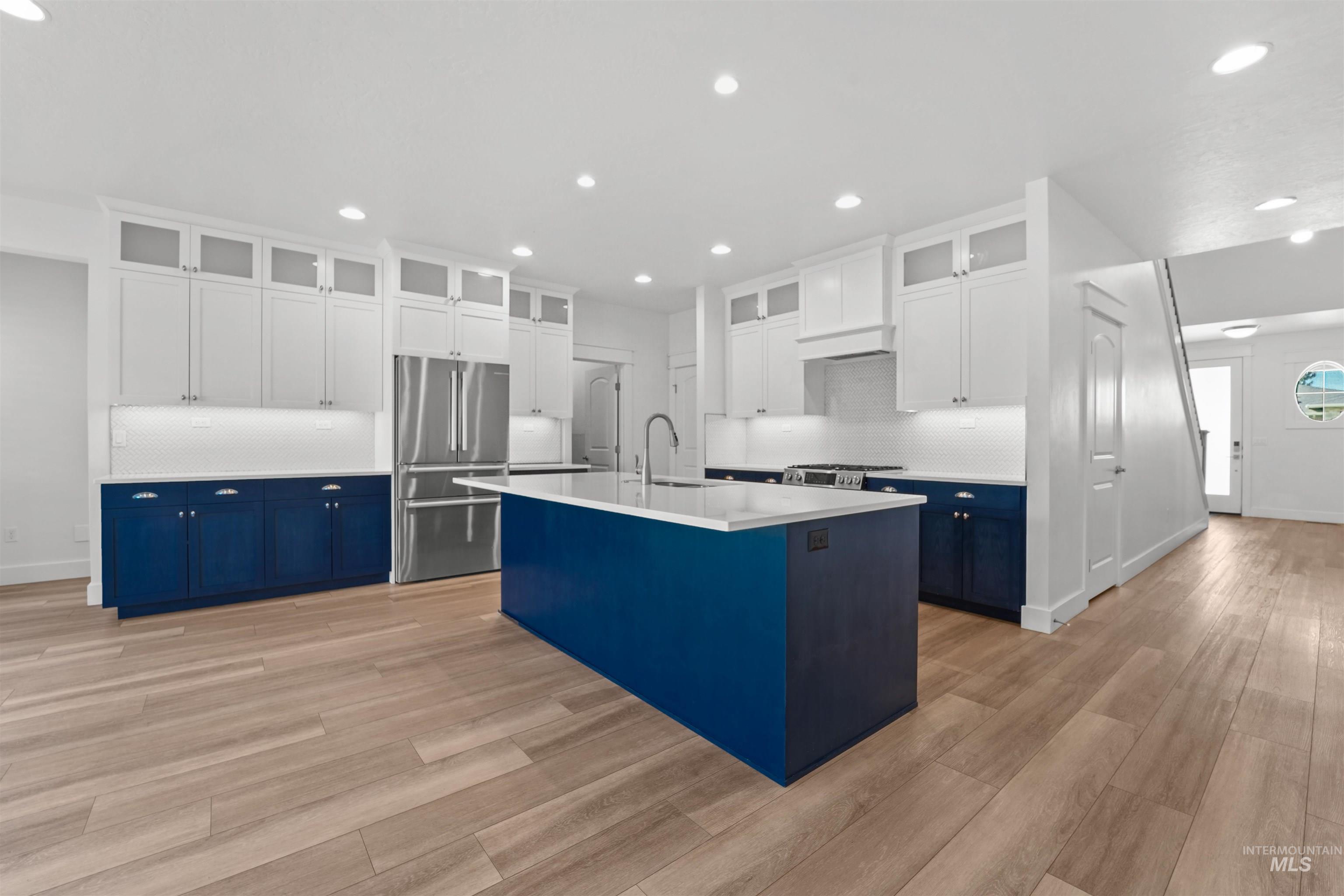 Kitchen featuring freestanding refrigerator, blue cabinetry, recessed lighting, decorative backsplash, and light wood finished floors