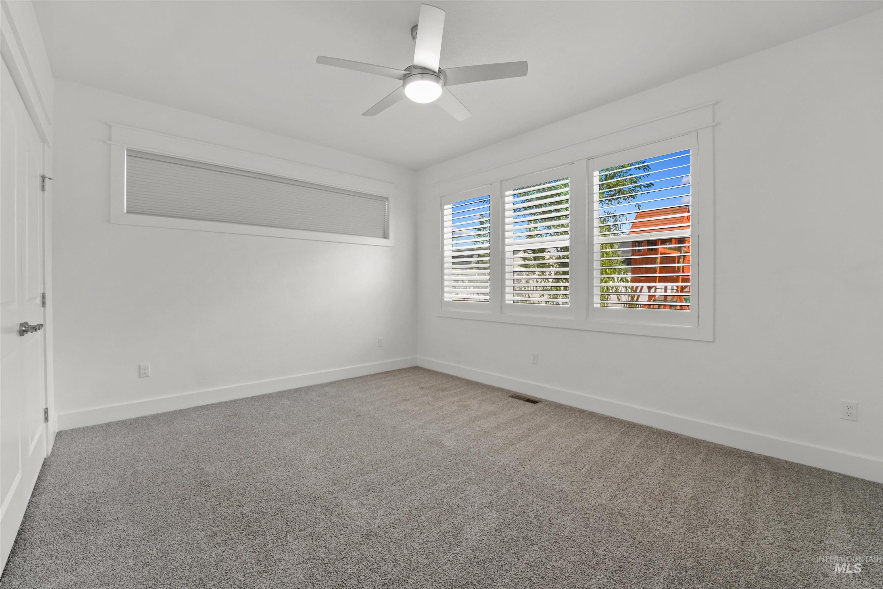 Carpeted empty room featuring baseboards and a ceiling fan