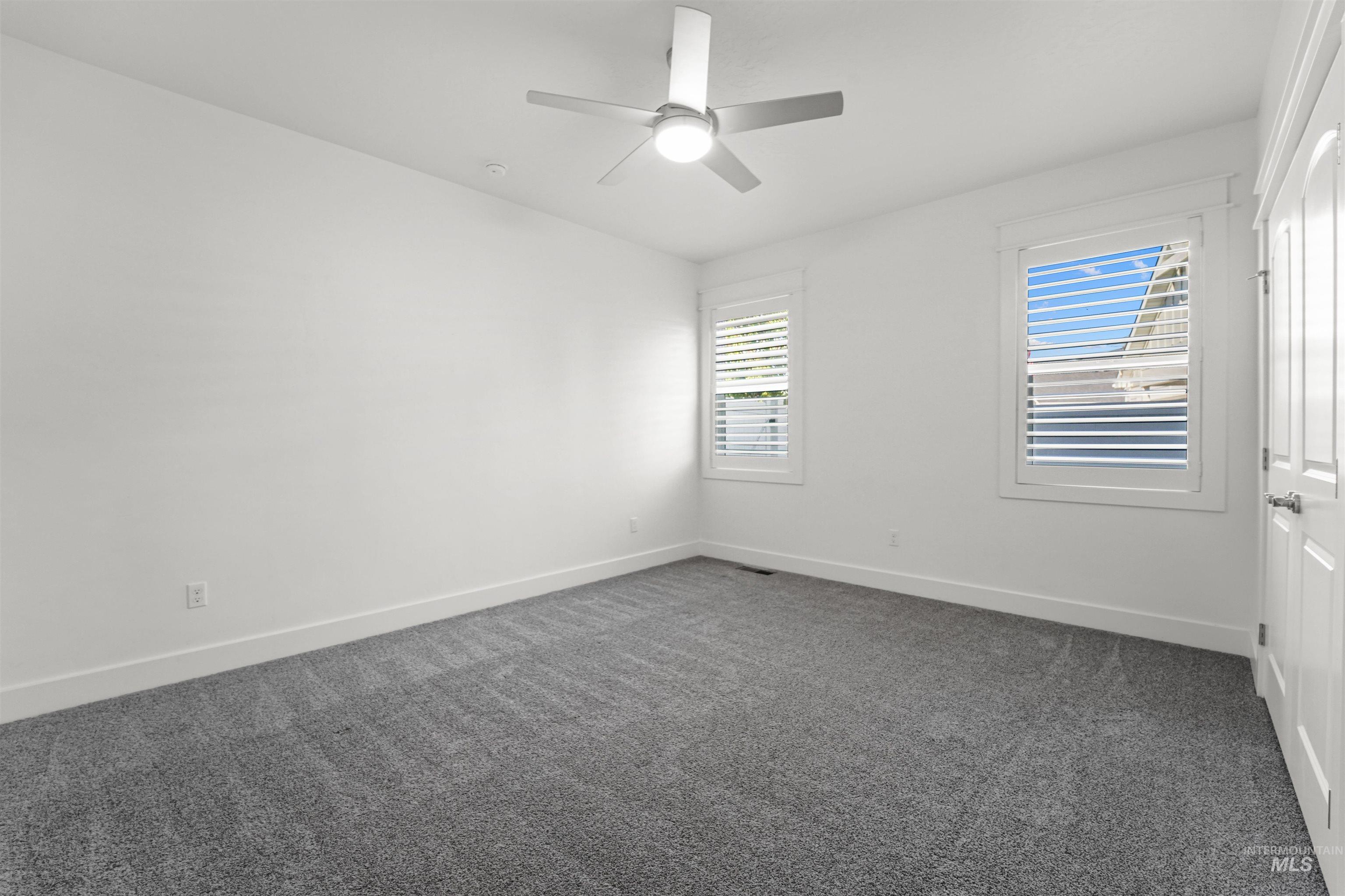 Empty room featuring dark carpet and ceiling fan
