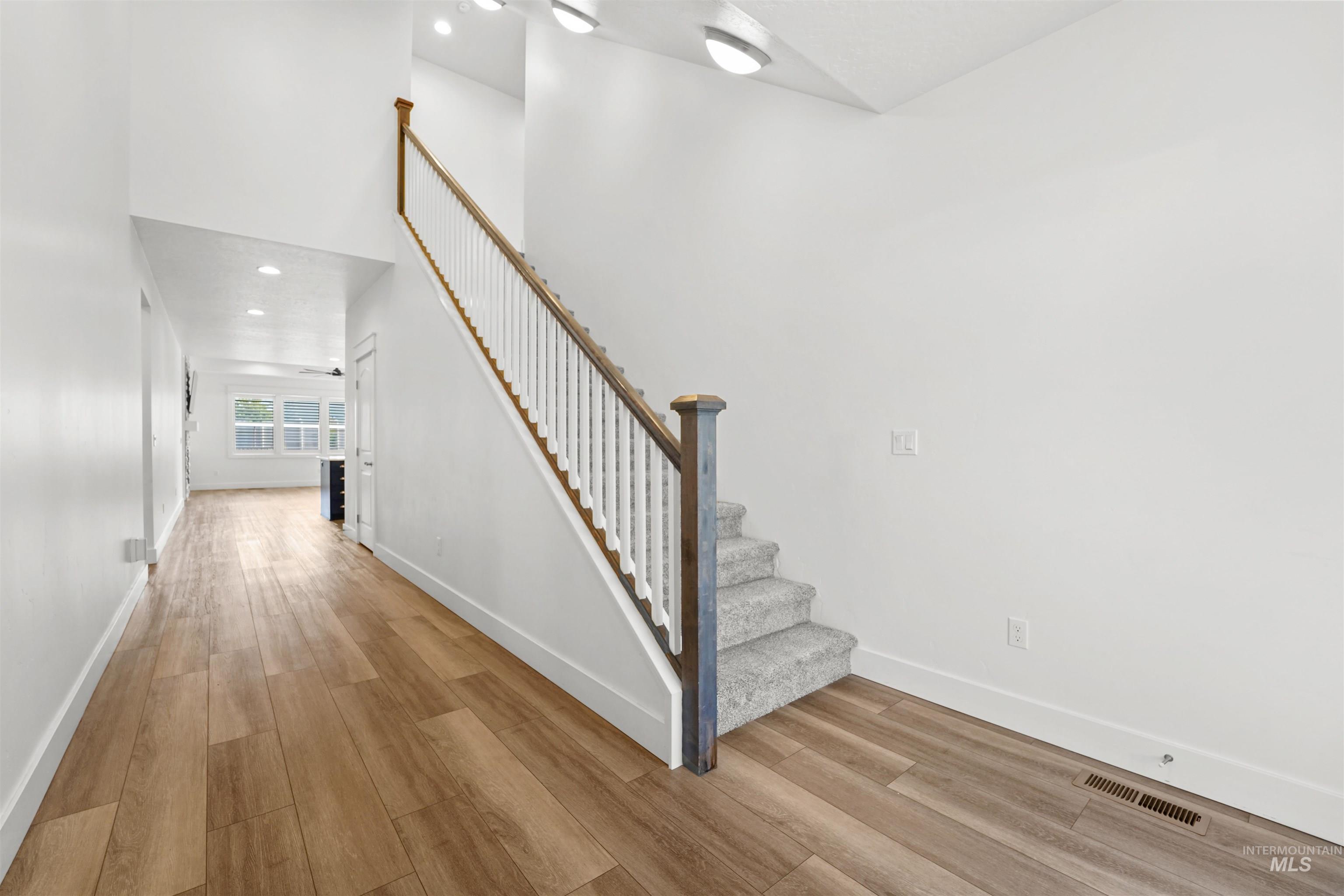 Stairs with wood finished floors and recessed lighting
