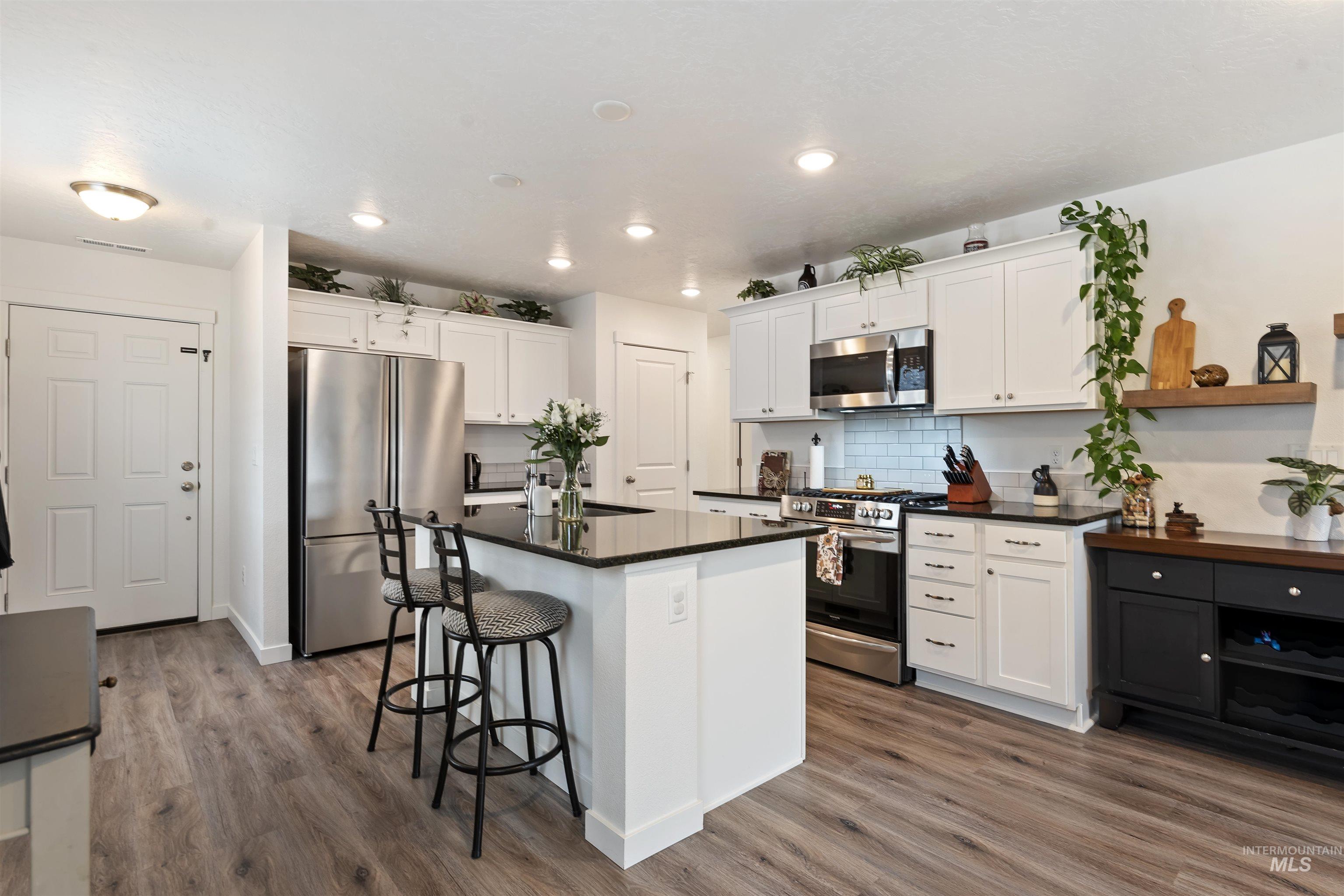 Kitchen with stainless steel appliances, white cabinets, a breakfast bar, recessed lighting, and open shelves