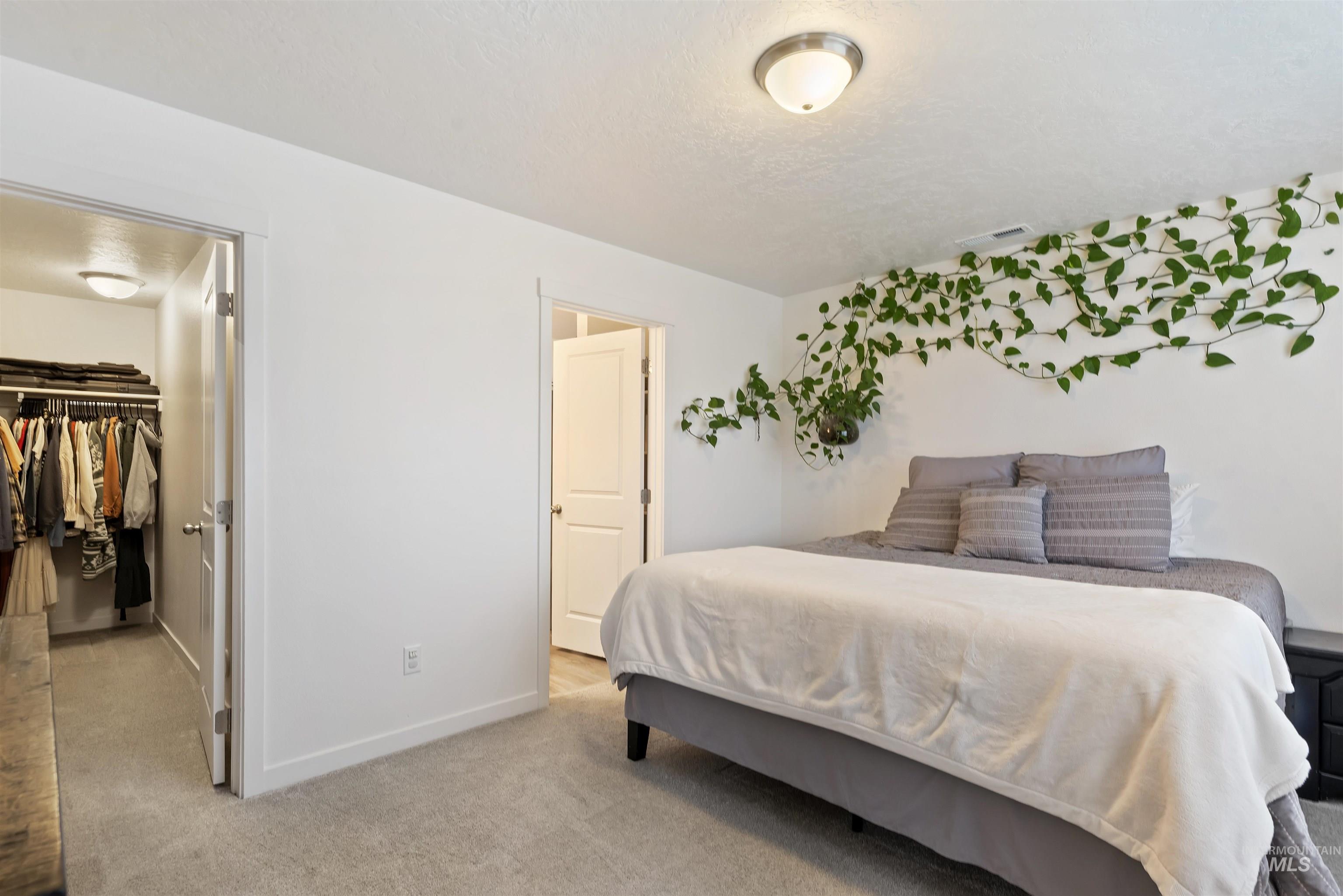 Bedroom featuring a walk in closet and light colored carpet