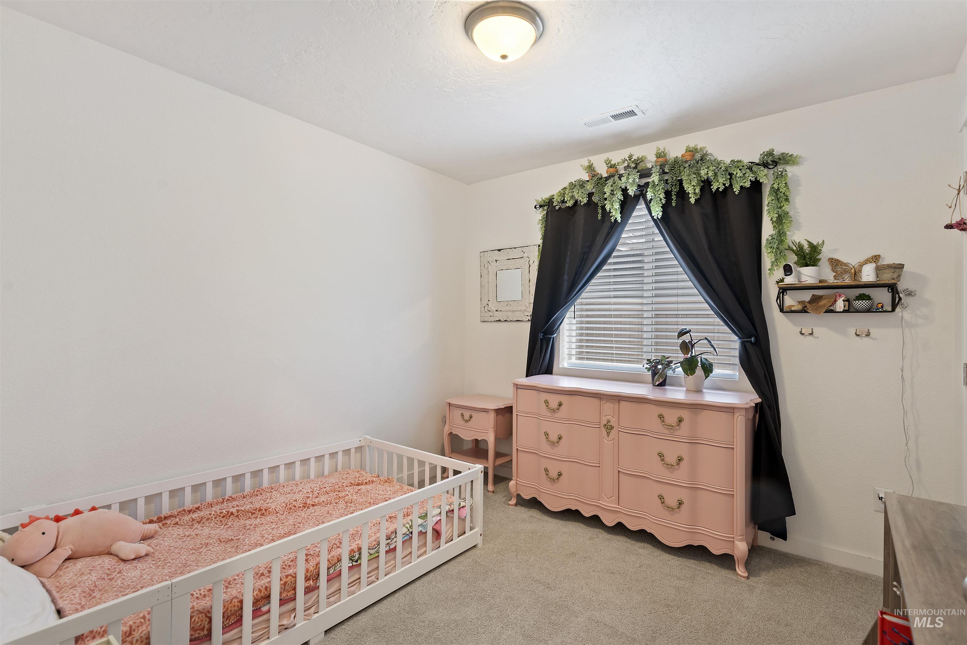 Bedroom featuring light carpet and a crib