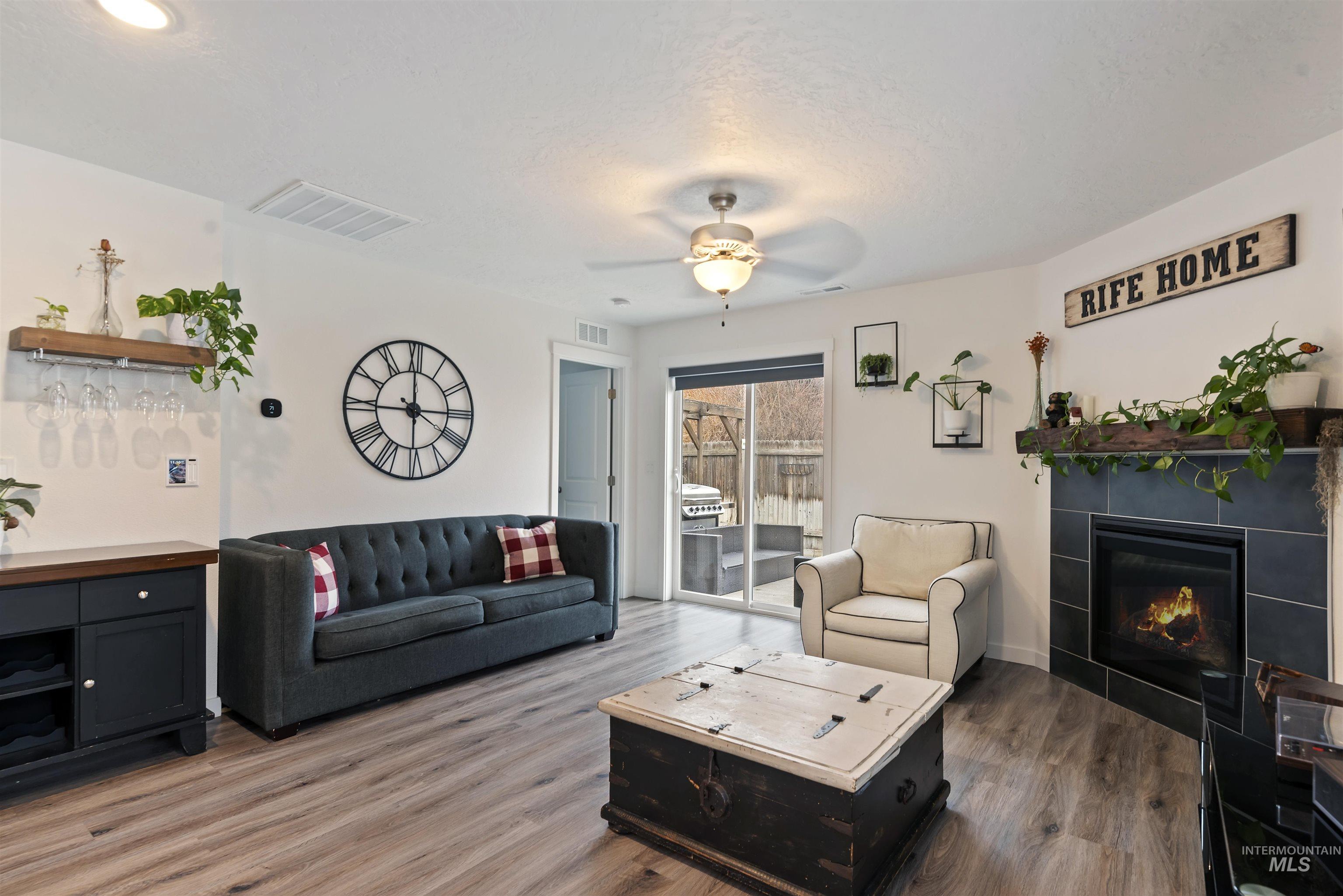 Living area featuring ceiling fan, a tile fireplace, and wood finished floors