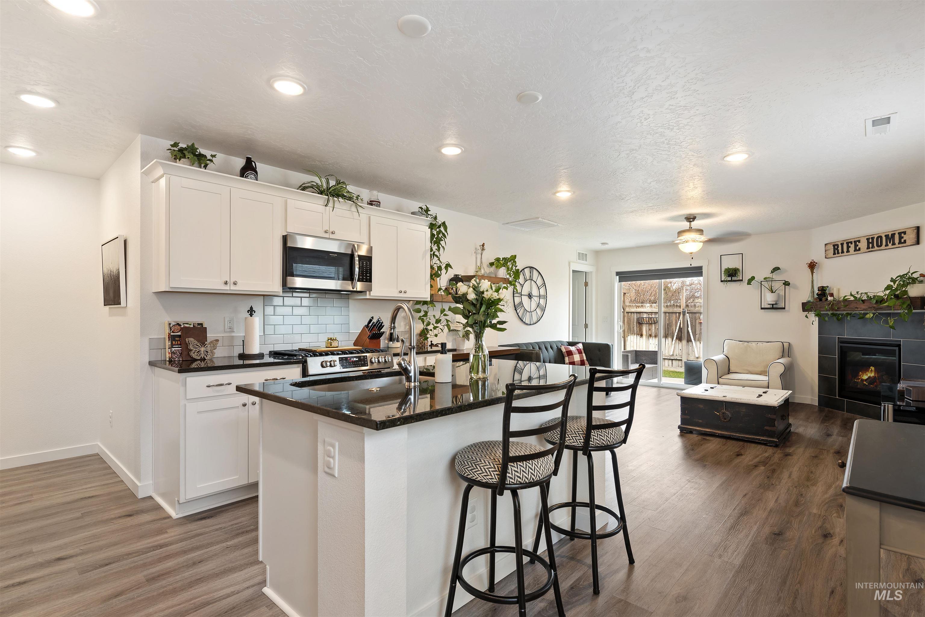 Kitchen with white cabinets, open floor plan, a fireplace, stainless steel appliances, and a breakfast bar