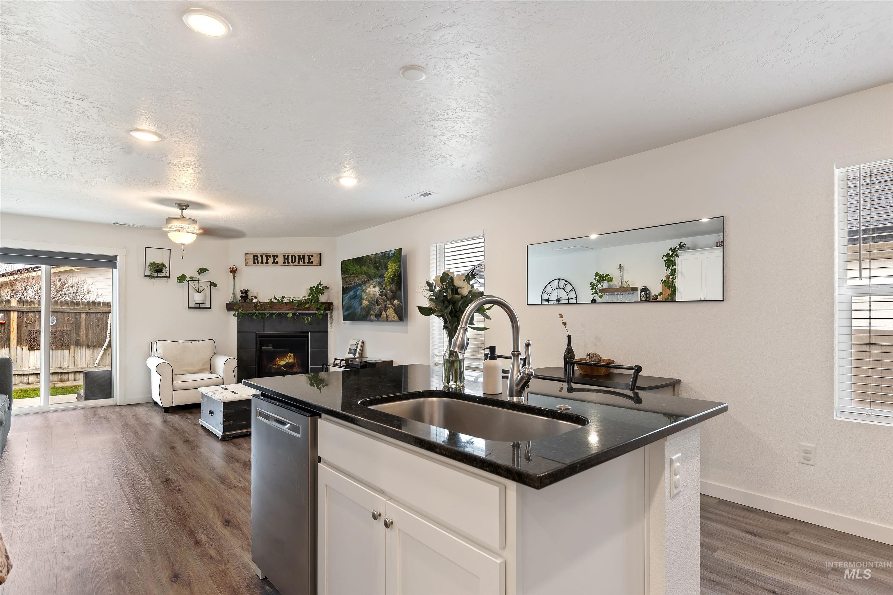 Kitchen with dark stone countertops, white cabinets, dark wood finished floors, healthy amount of natural light, and a textured ceiling
