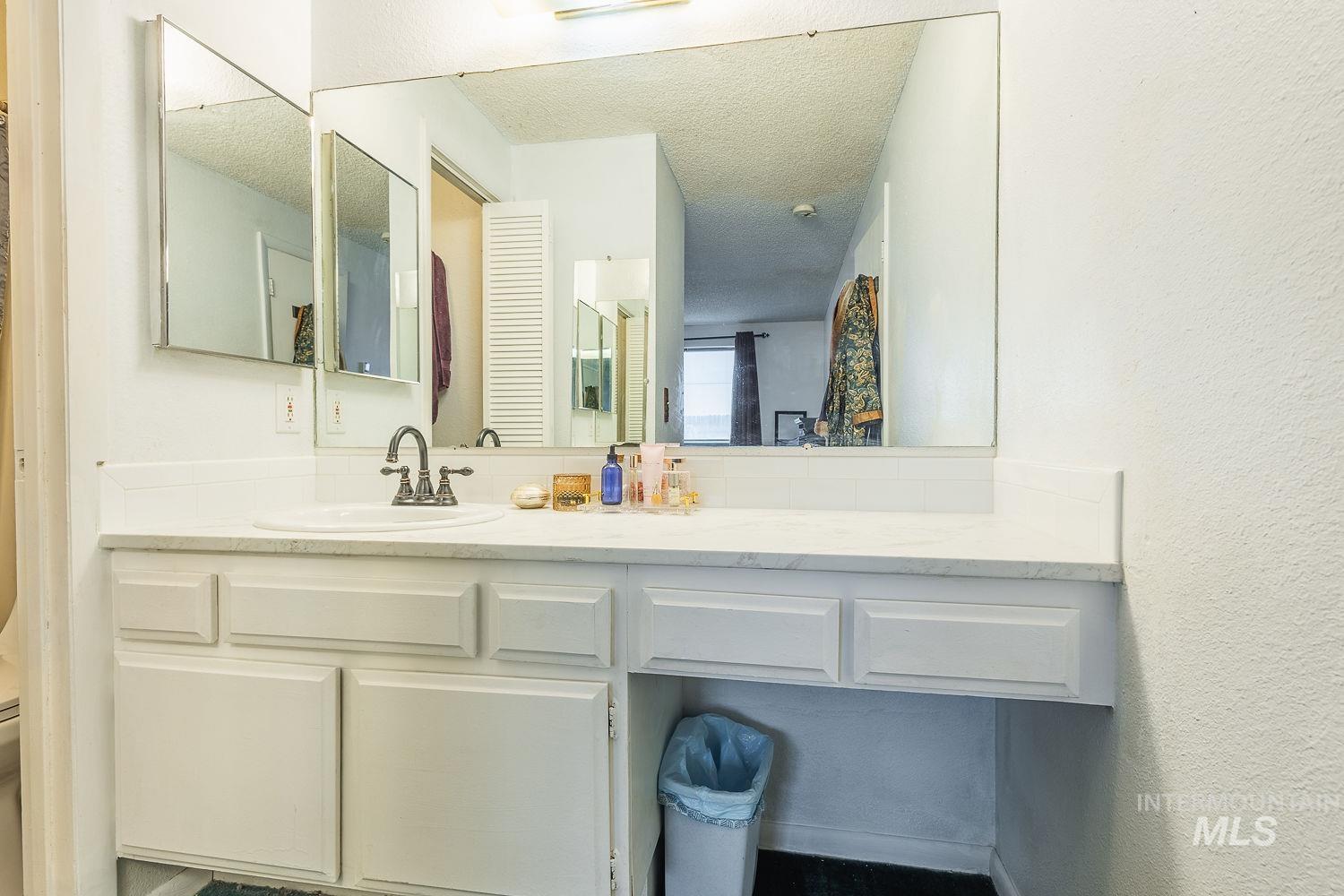 Bathroom with vanity, a textured wall, and a textured ceiling