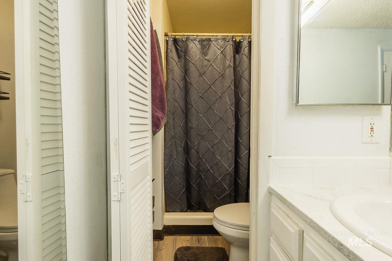 Full bathroom with a stall shower, vanity, and a closet