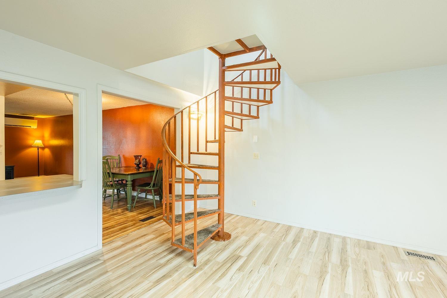 Staircase with wood finished floors and an AC wall unit