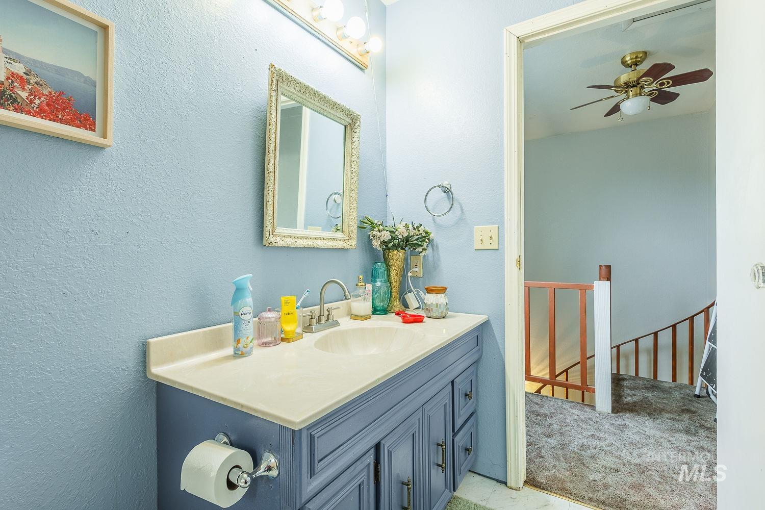 Bathroom with vanity, light colored carpet, ceiling fan, and a textured wall
