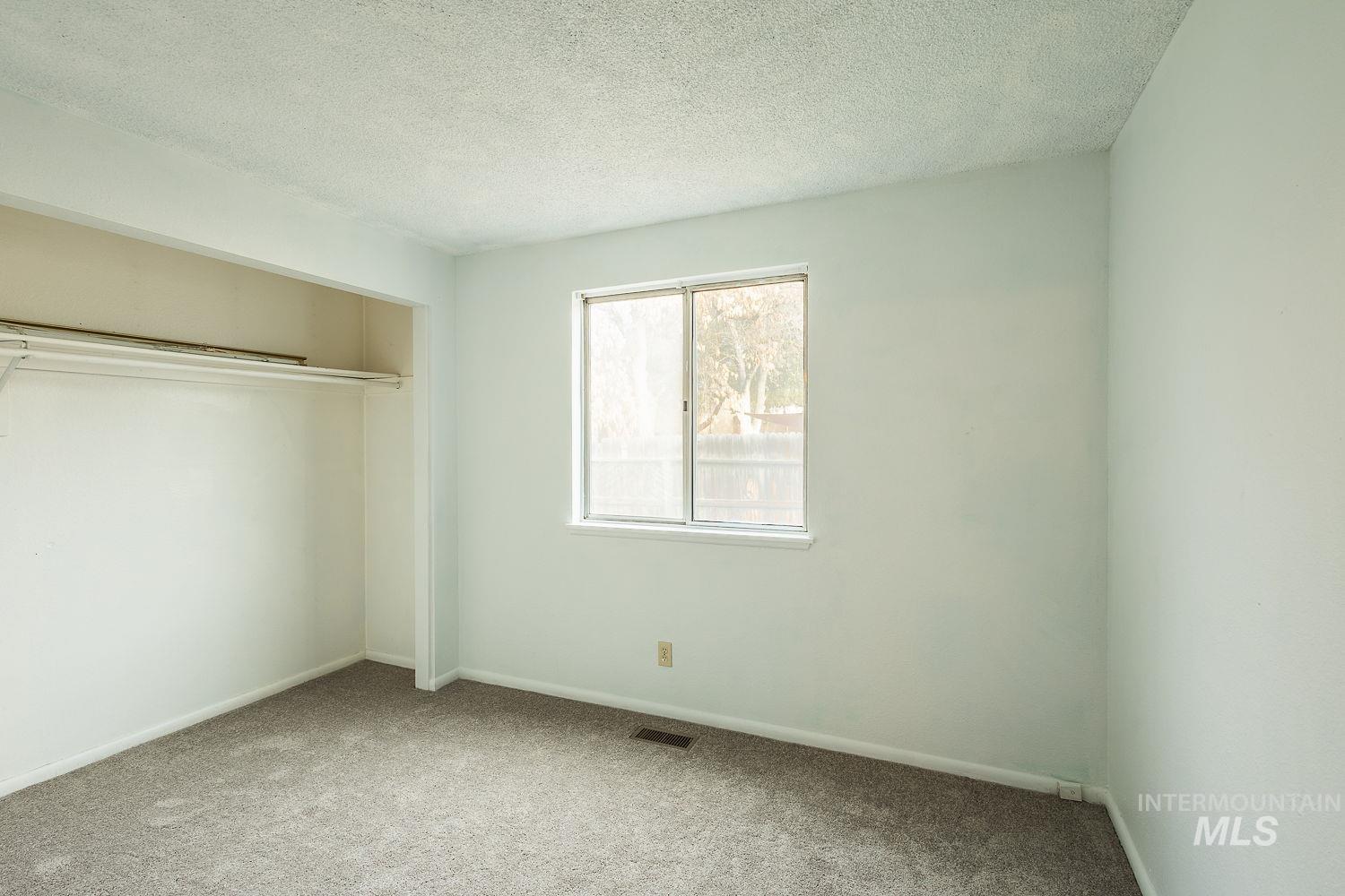 Unfurnished bedroom featuring a textured ceiling, carpet flooring, and a closet