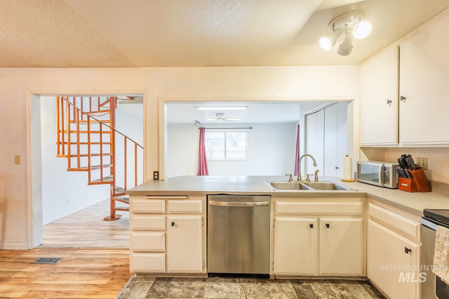 Kitchen with light countertops, appliances with stainless steel finishes, a textured ceiling, a peninsula, and light wood-style flooring