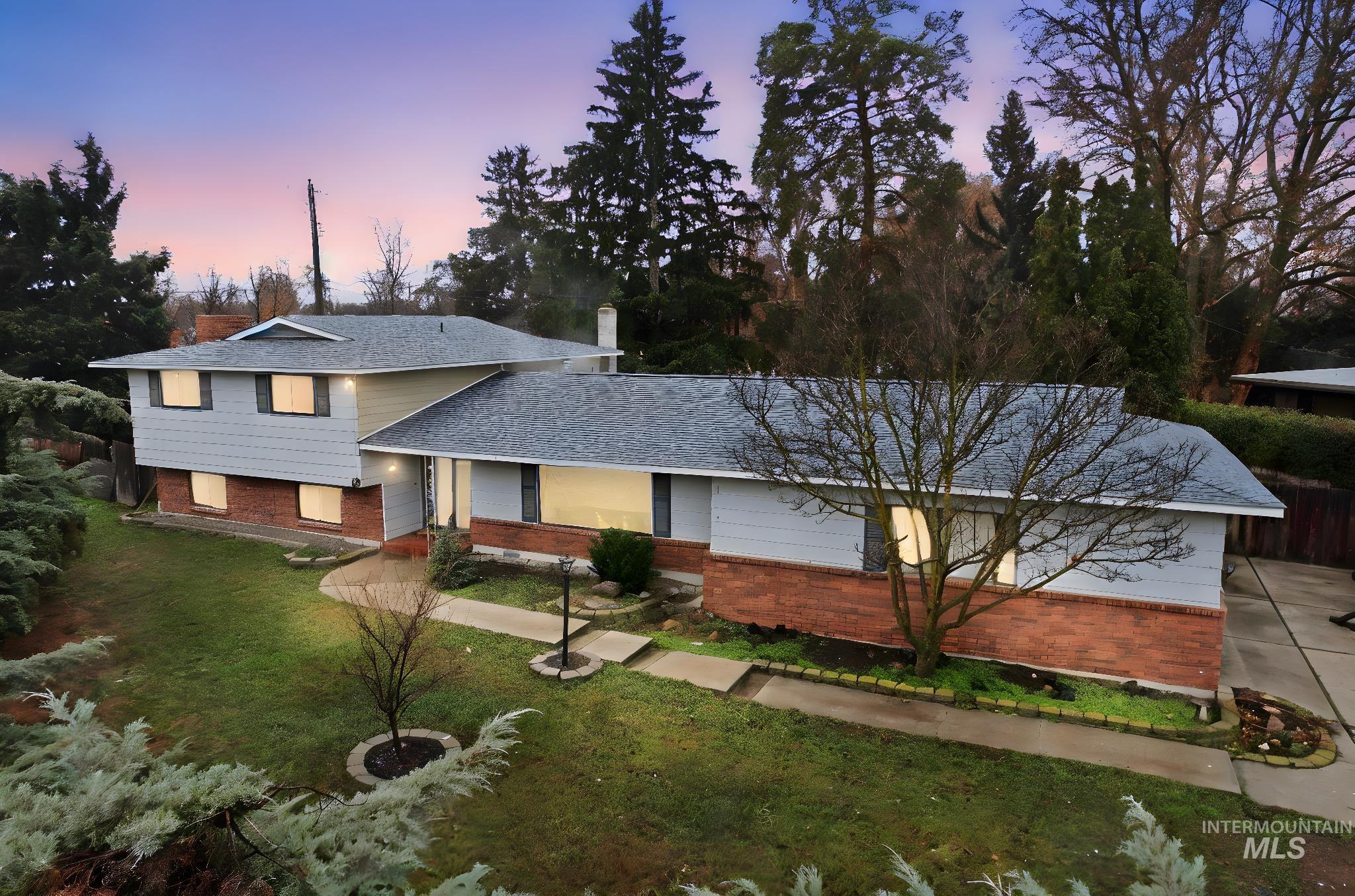 Tri-level home featuring a lawn, brick siding, and roof with shingles