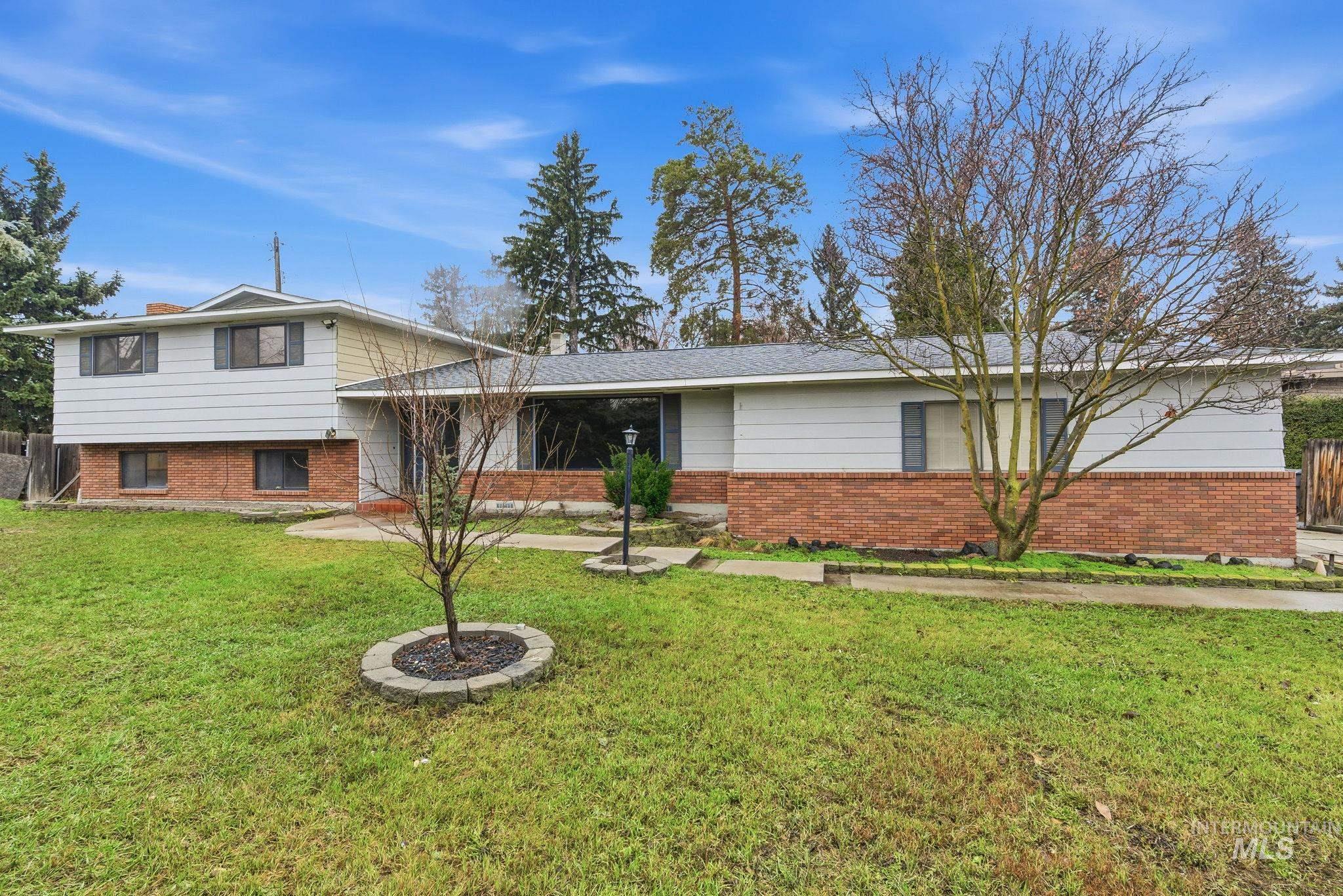 Tri-level home featuring a front lawn and brick siding