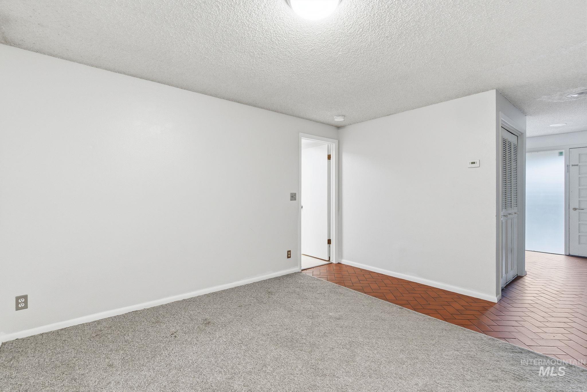 Carpeted empty room featuring a textured ceiling and baseboards