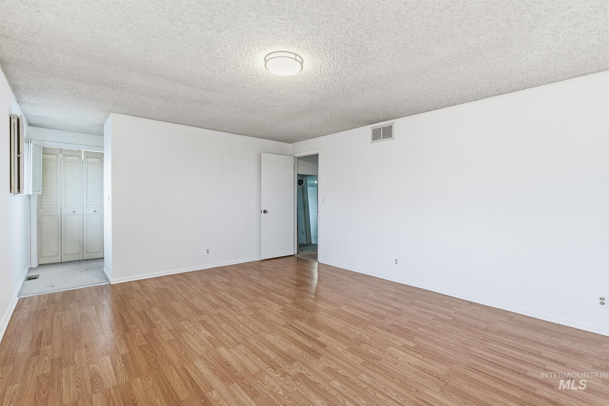 Empty room with a textured ceiling and light wood finished floors