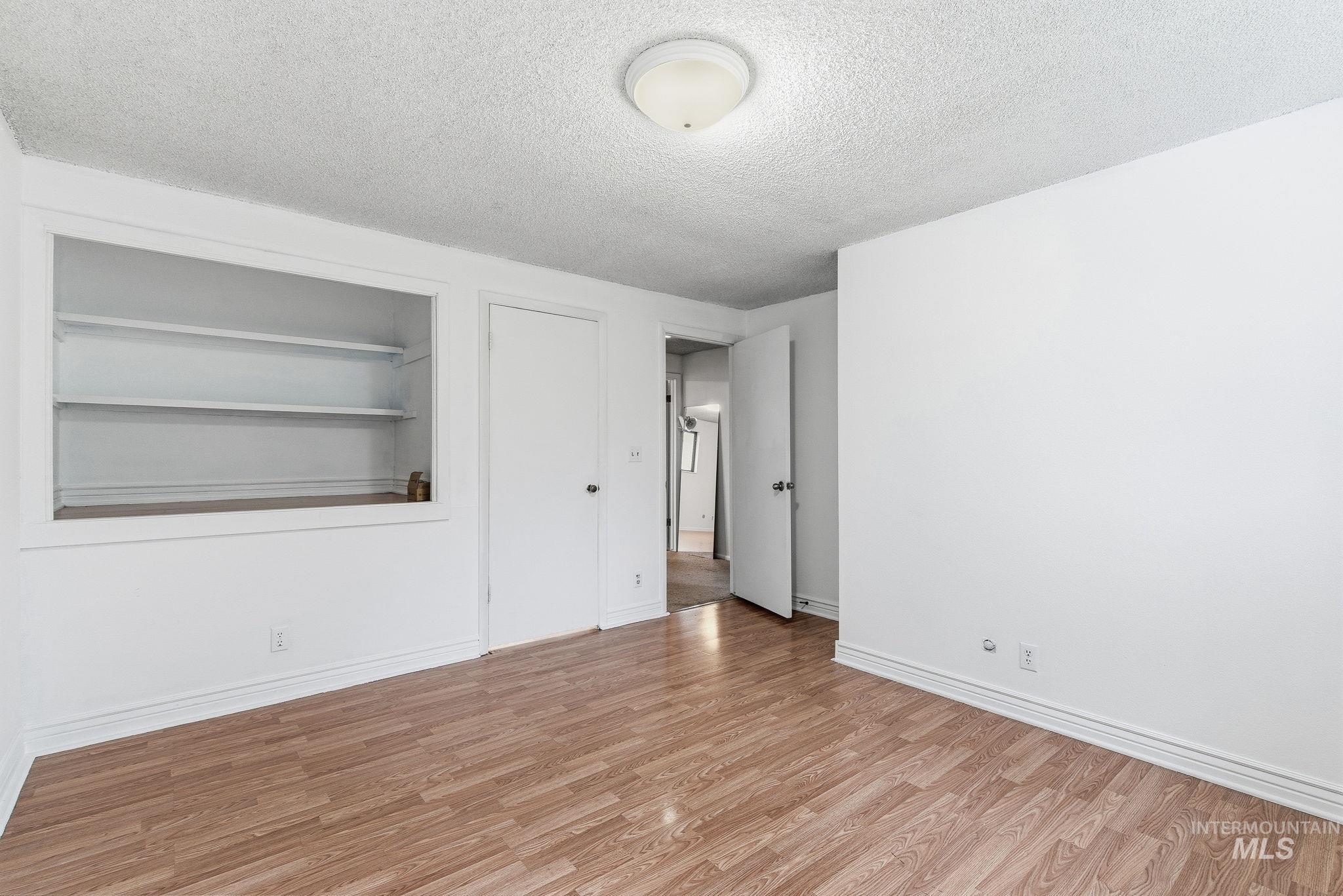 Spare room with a textured ceiling, light wood-style floors, and built in features
