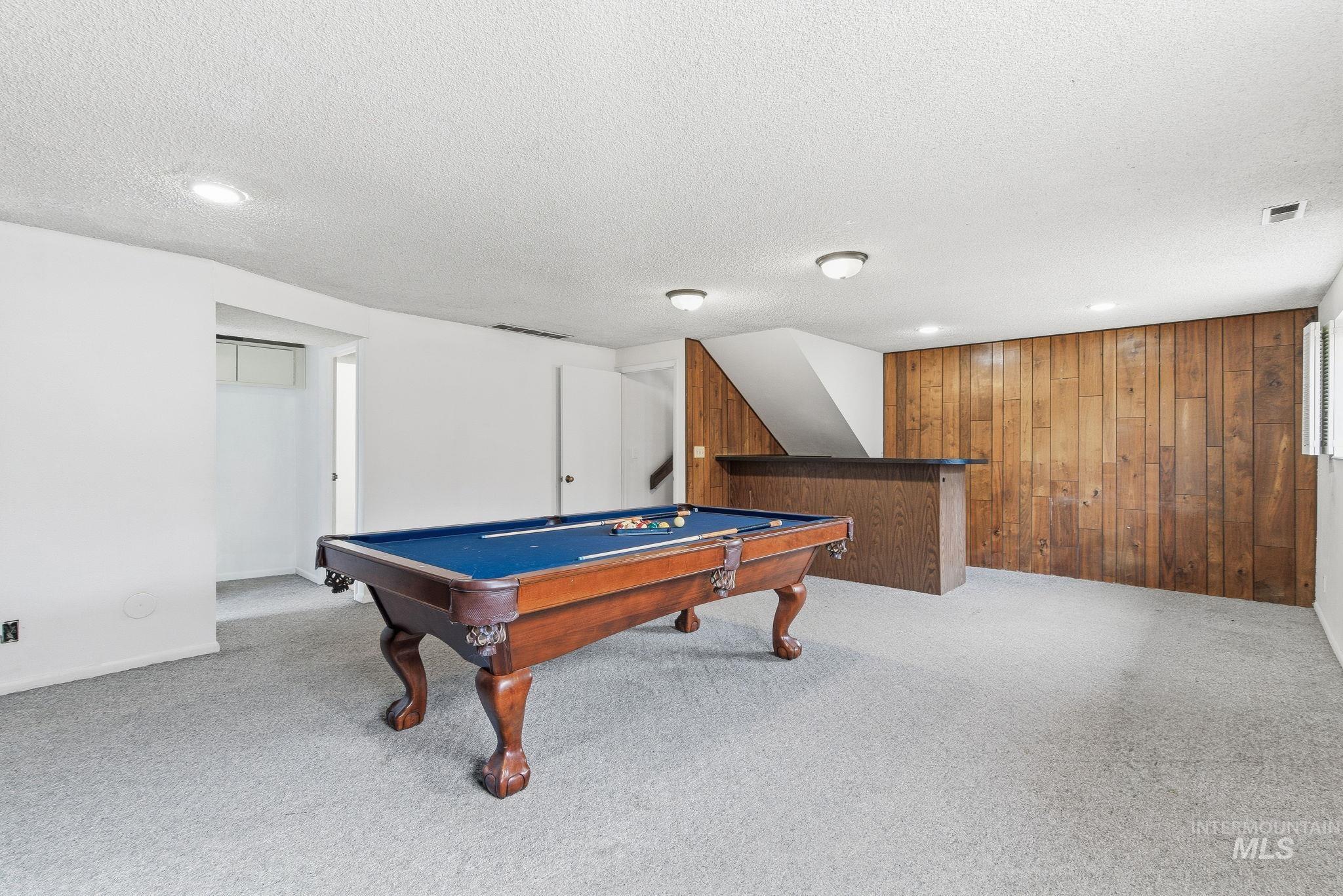 Playroom featuring a bar, light colored carpet, recessed lighting, a textured ceiling, and wood walls