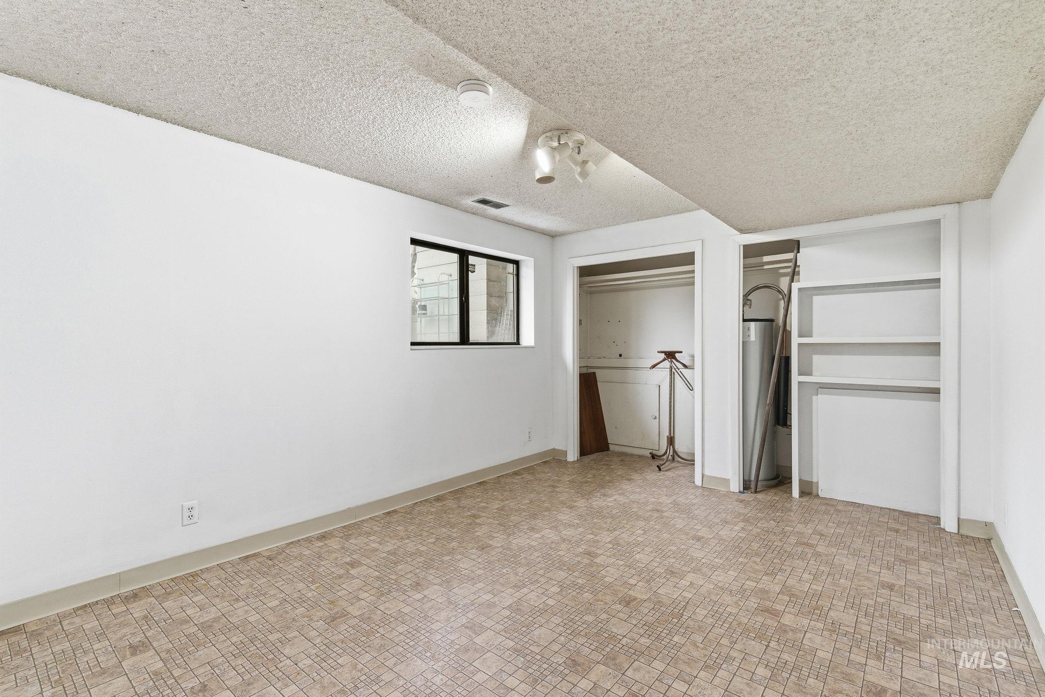 4th bedroom featuring two closets, a textured ceiling, and water heater