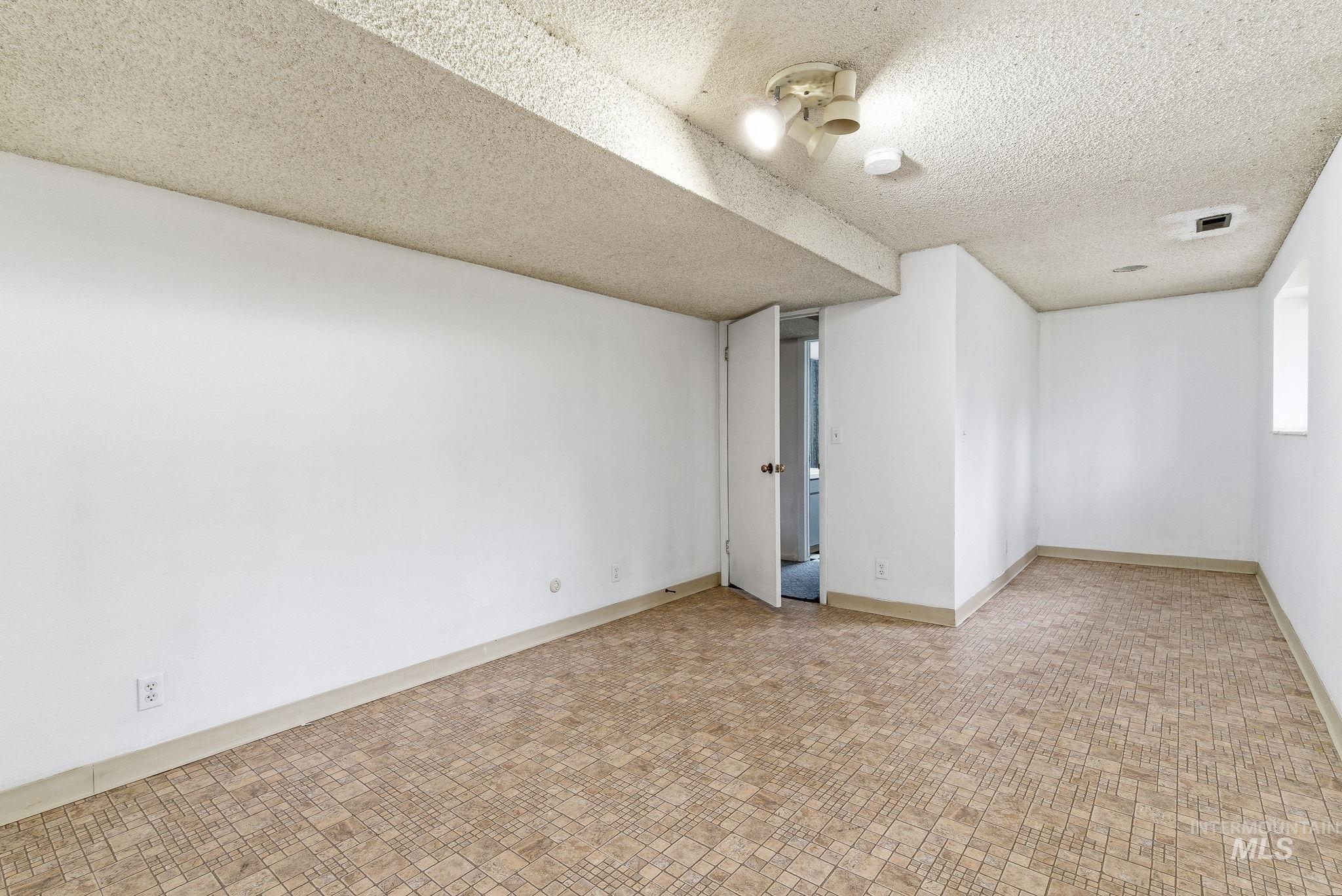 4th bedroom featuring a textured ceiling and baseboards