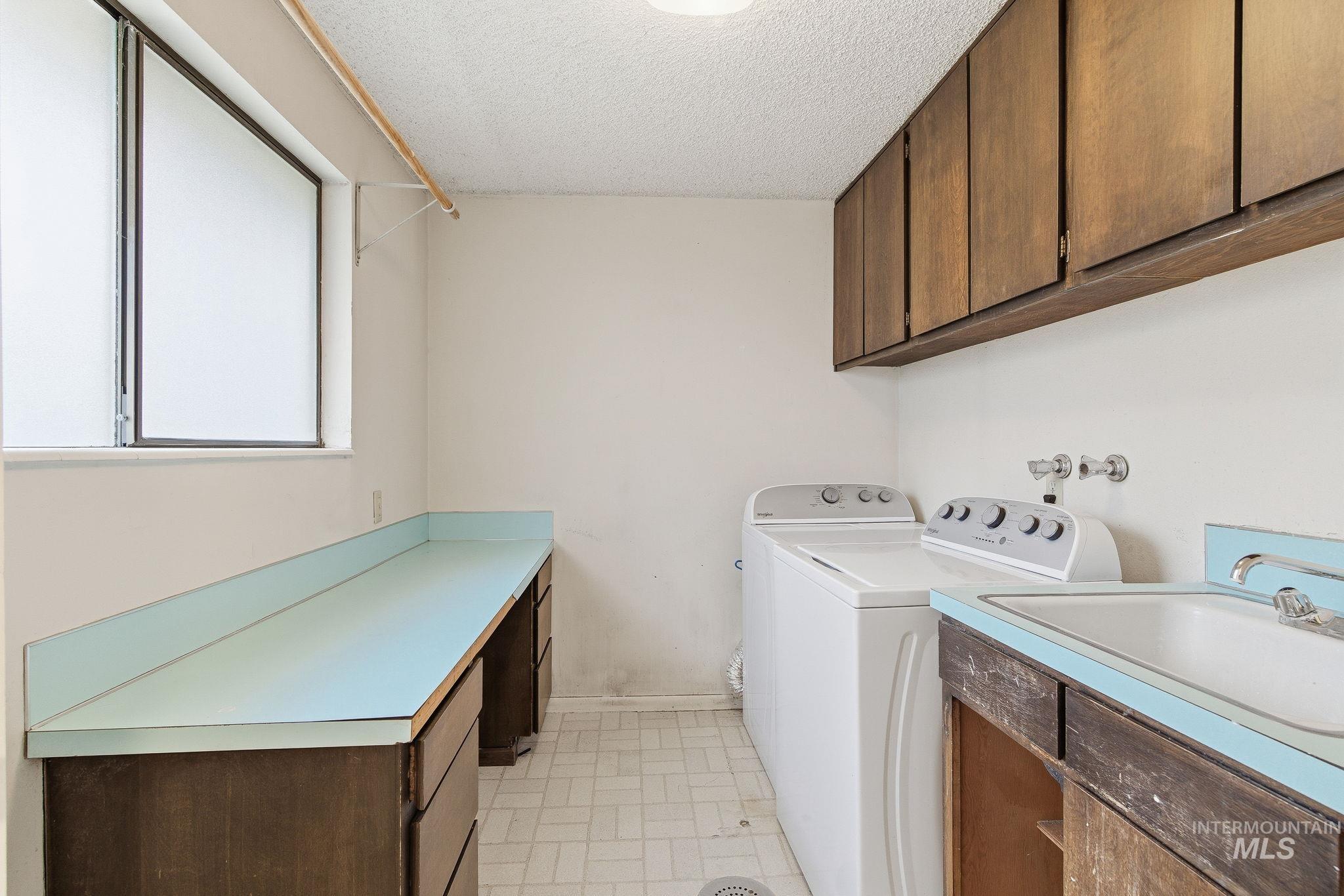 Washroom featuring a textured ceiling, cabinet space, and washing machine and dryer