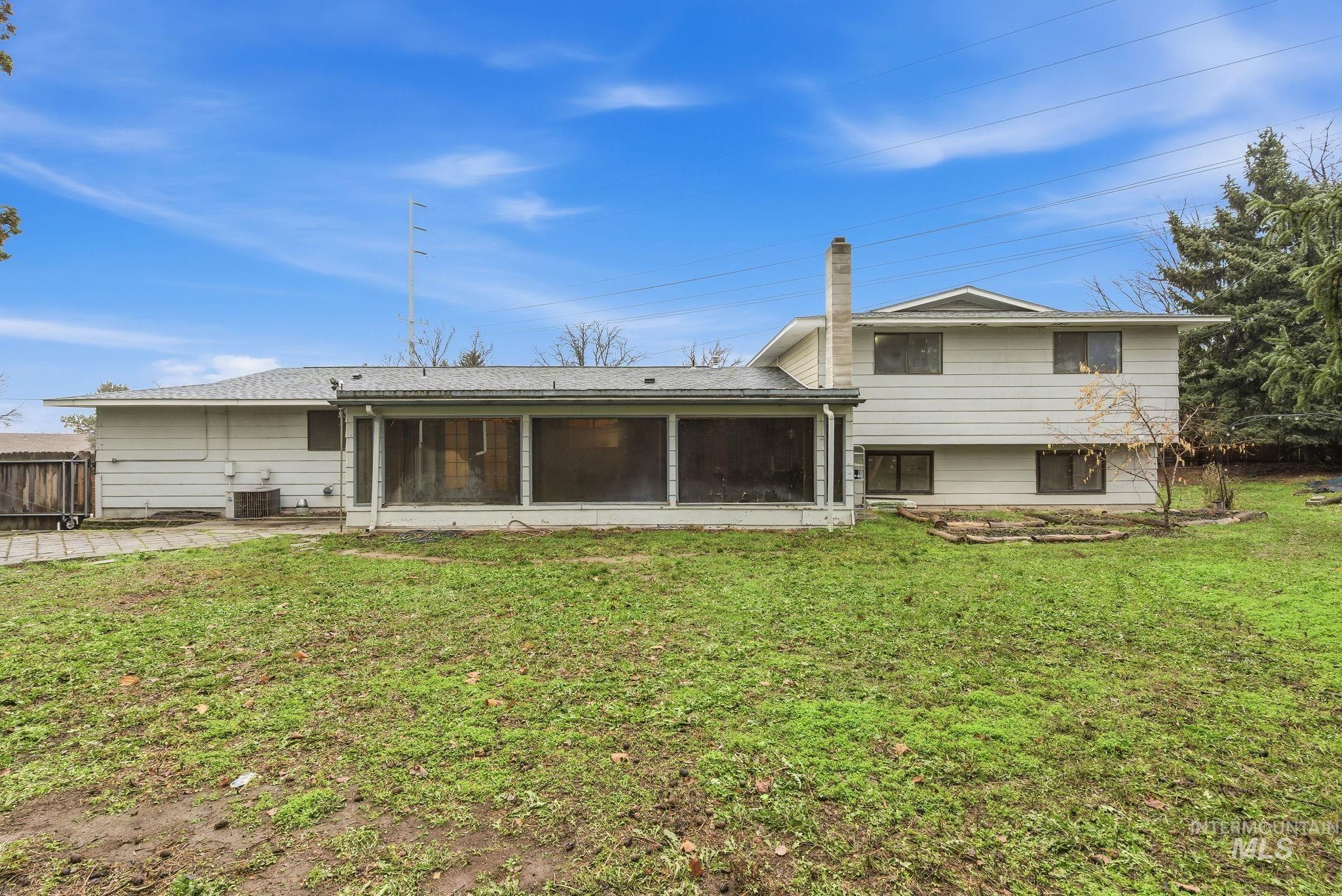 Rear view of house with a yard, a chimney, a sunroom, and a patio