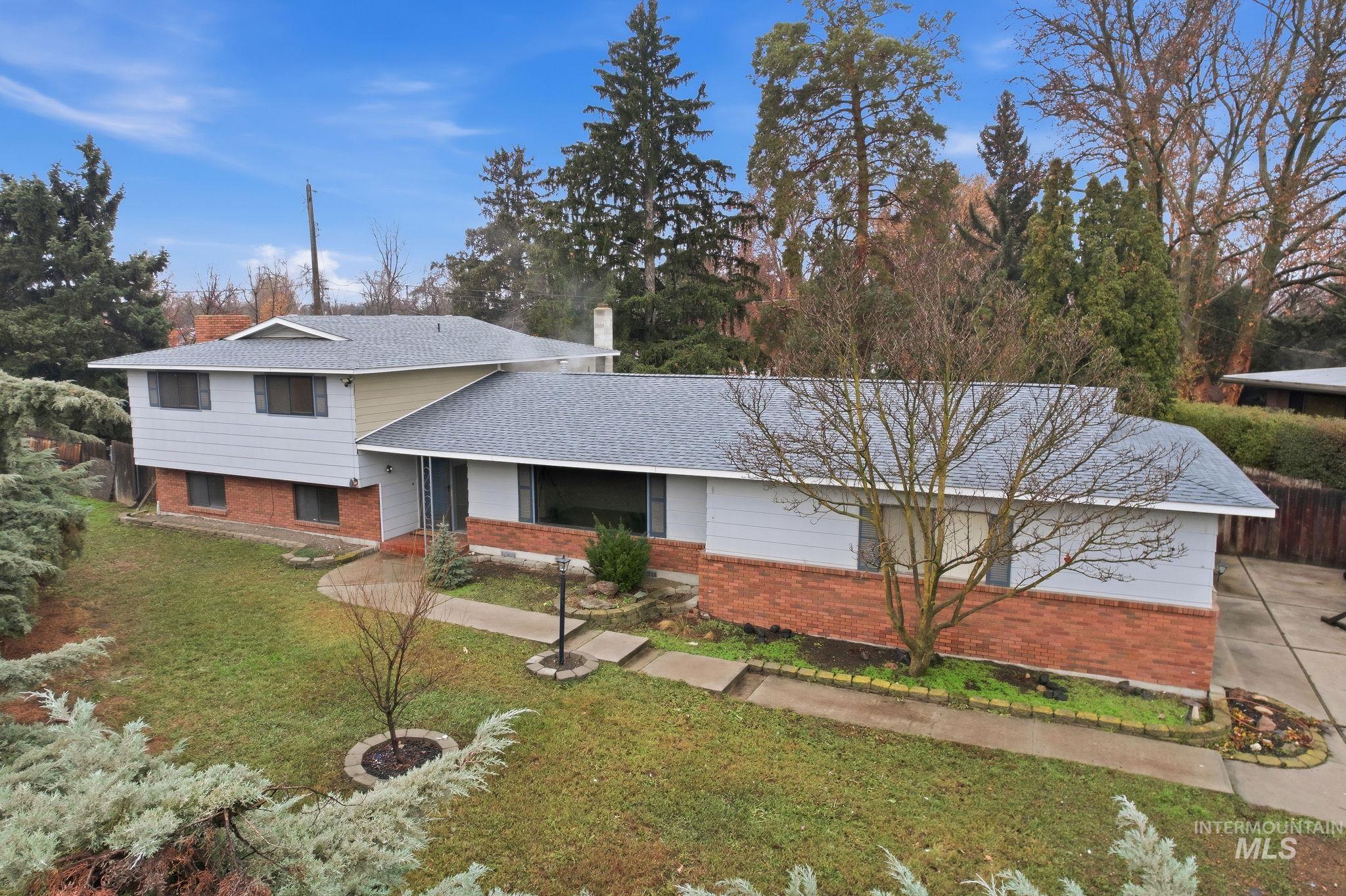 Split level home with brick siding, a front yard, and a shingled roof