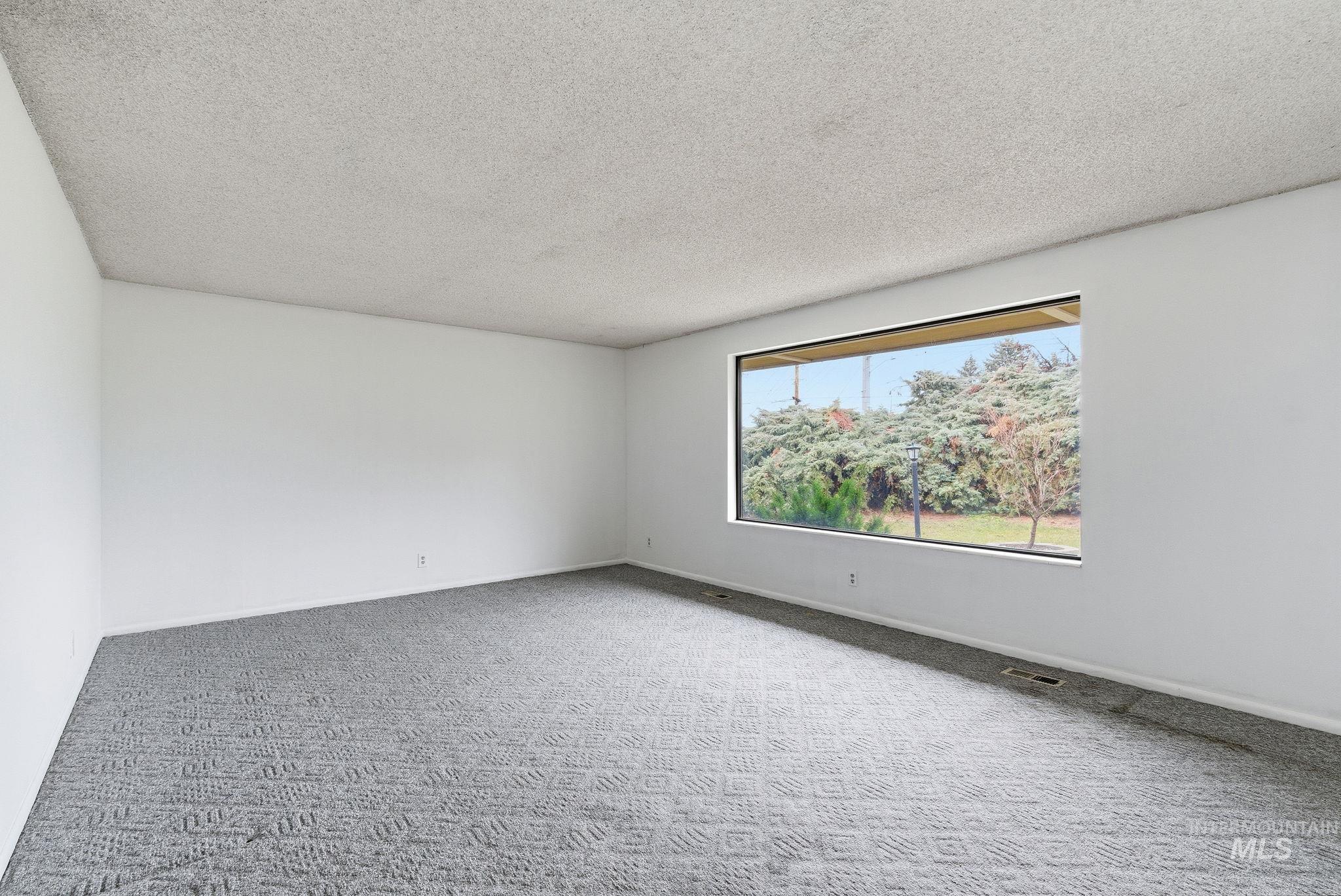 Empty room with a textured ceiling and carpet flooring