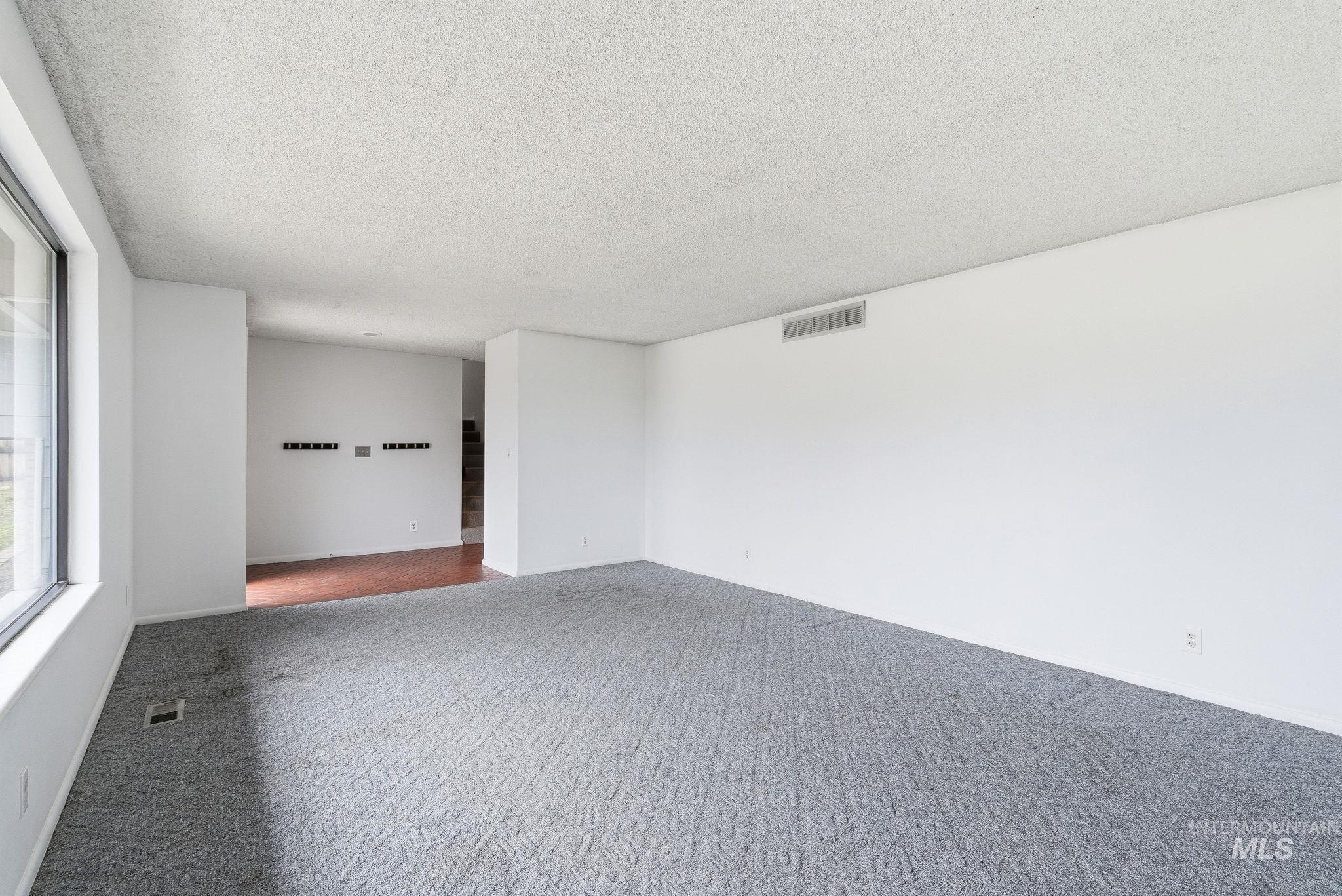 Carpeted spare room with a textured ceiling and baseboards