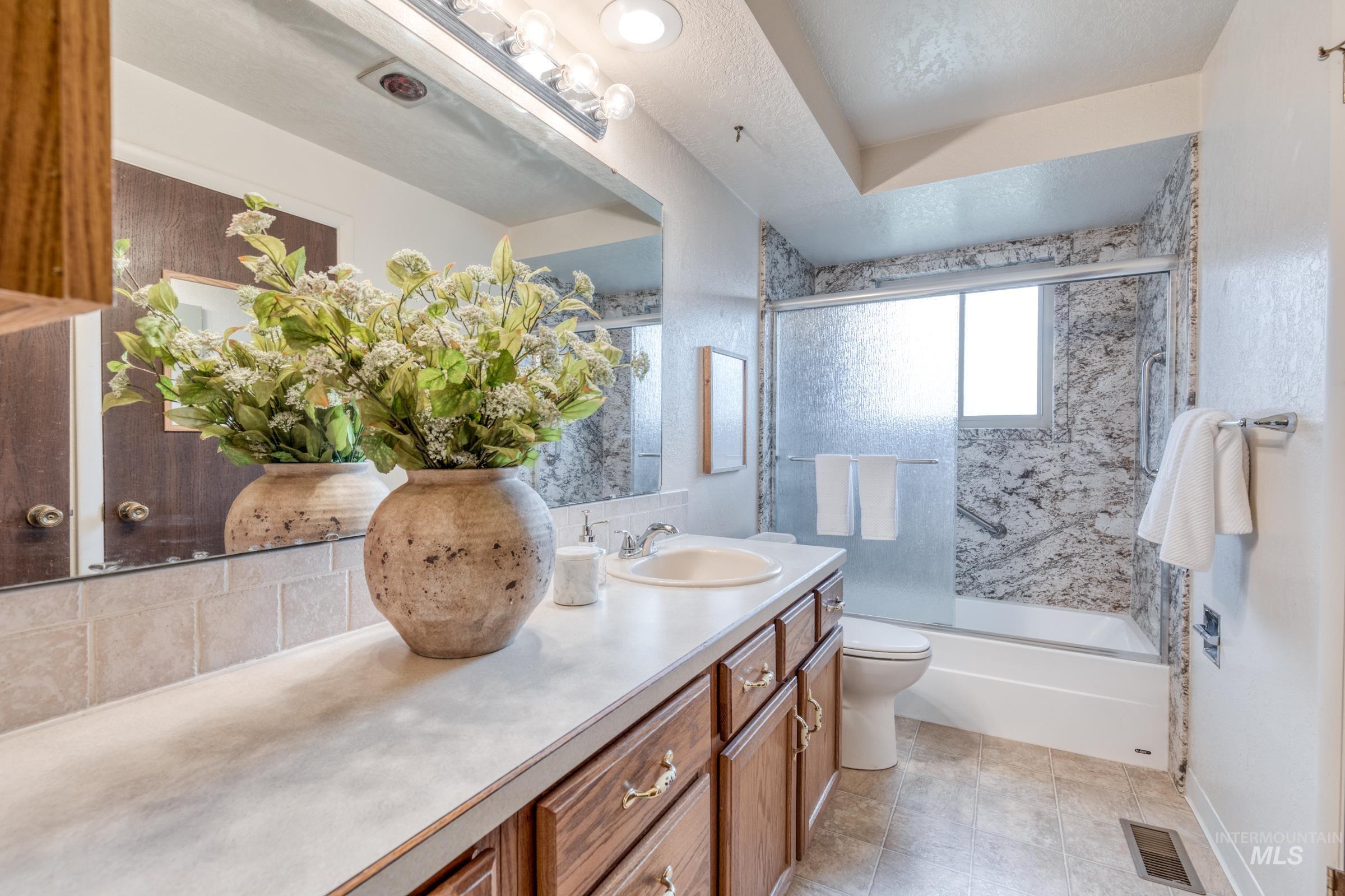 Bathroom with shower / bath combination with glass door and vanity