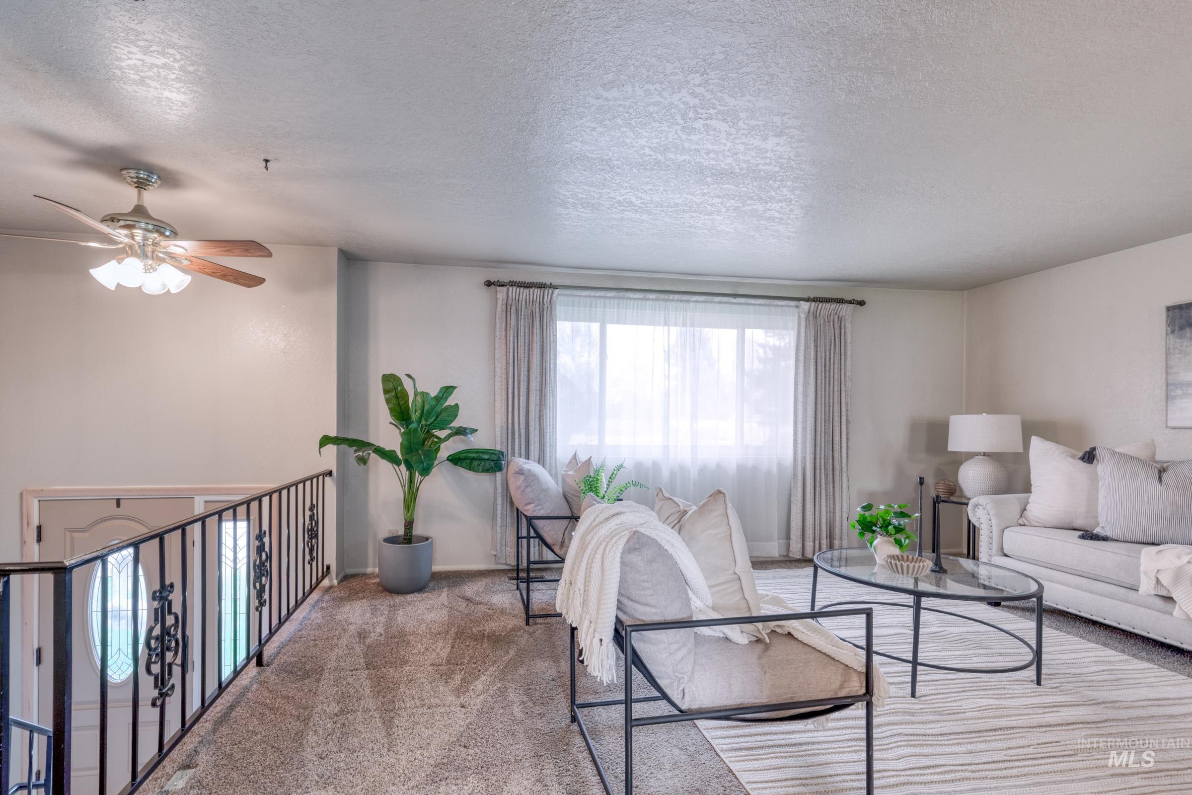 Carpeted living room featuring a textured ceiling and a ceiling fan