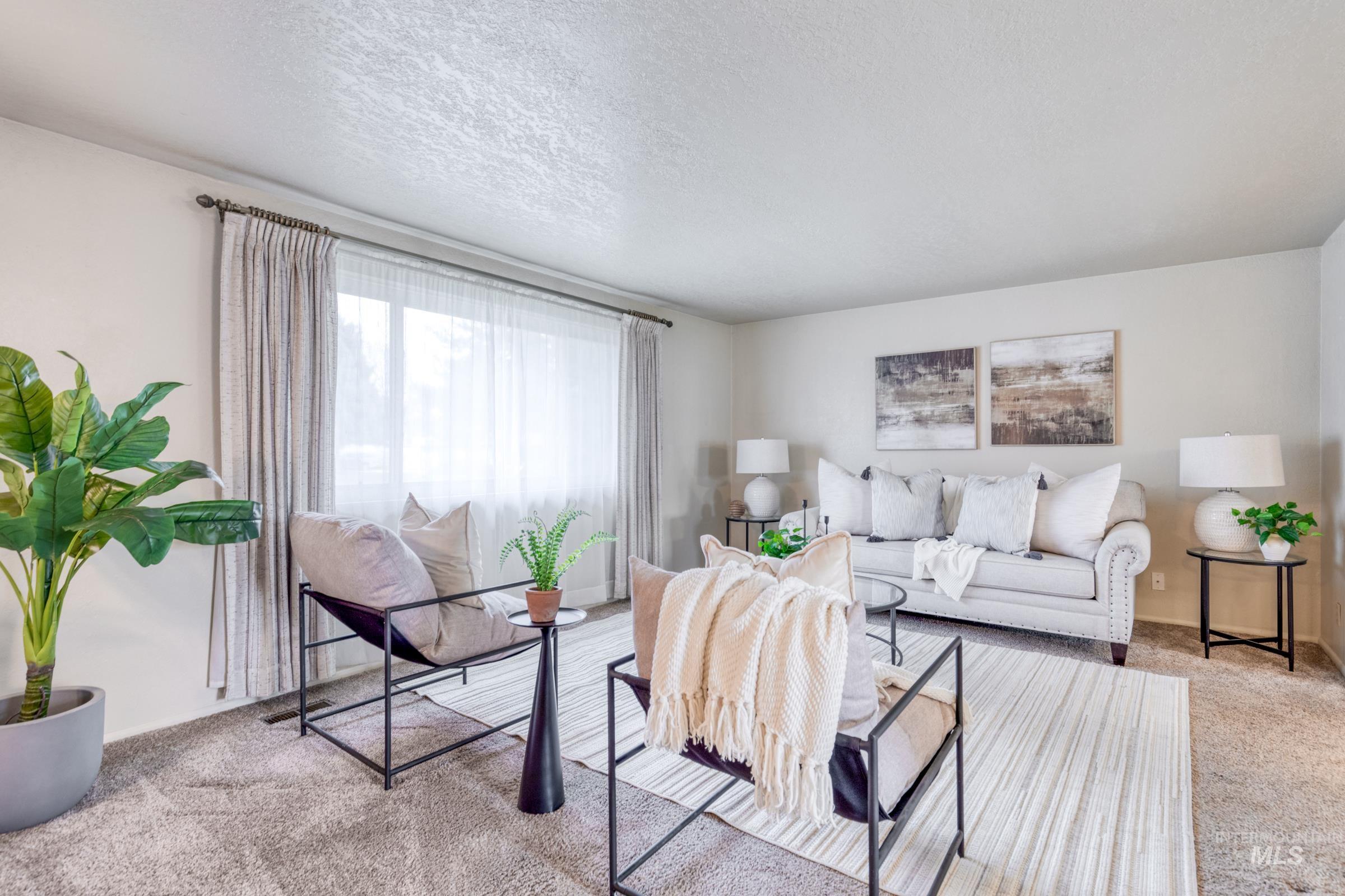 Carpeted living room with a textured ceiling and baseboards