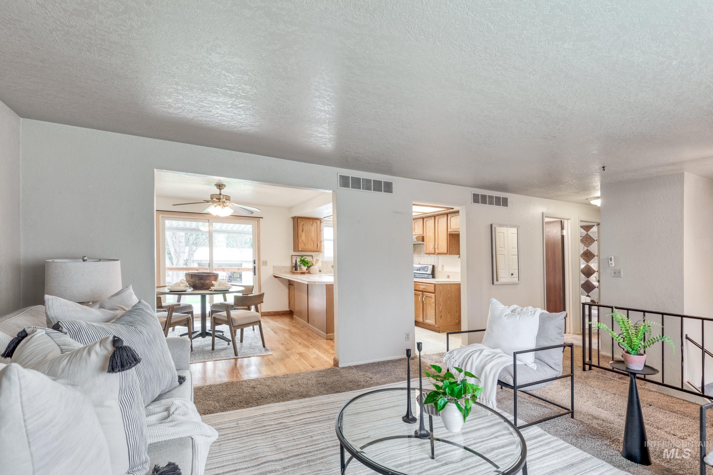 Living area with light carpet, a textured ceiling, and a ceiling fan