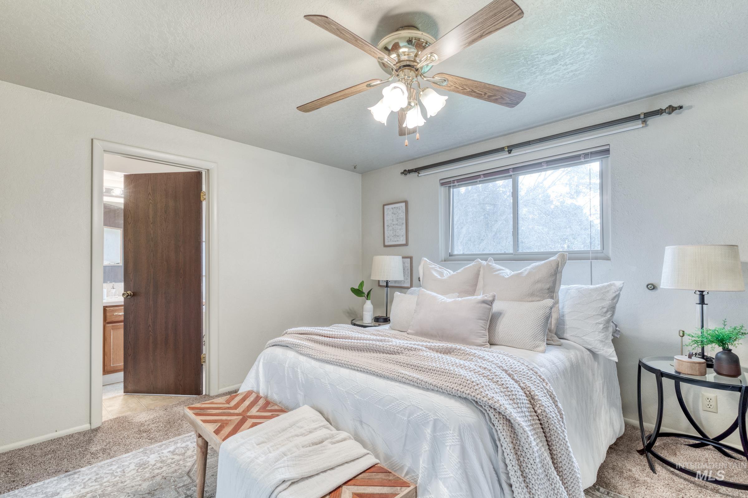 Bedroom with light colored carpet, a textured ceiling, a ceiling fan, and connected bathroom