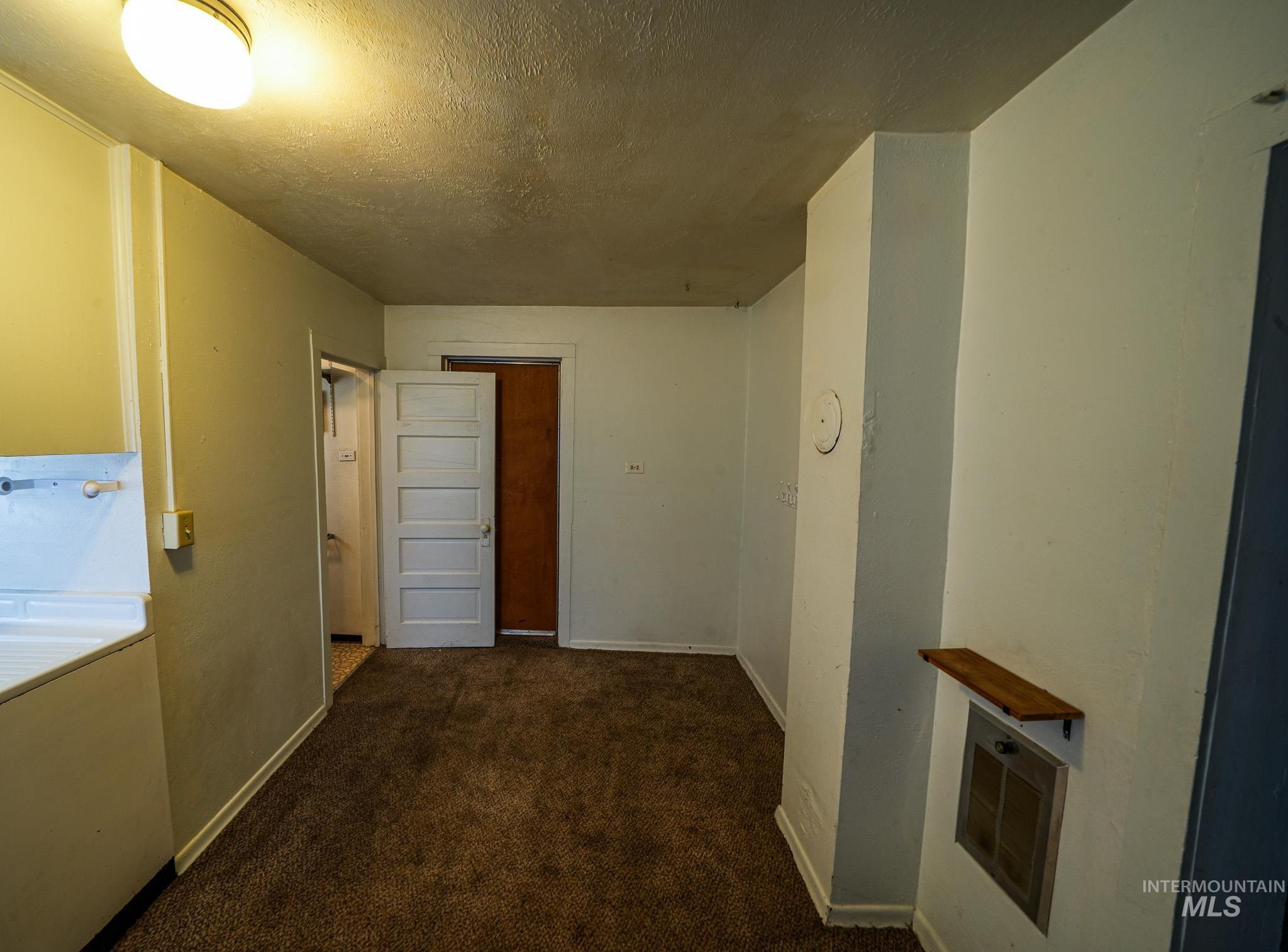 Corridor with dark colored carpet and a textured ceiling