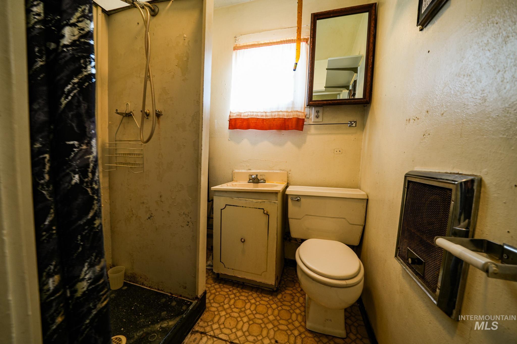 Bathroom with a stall shower, vanity, light floors, and heating unit