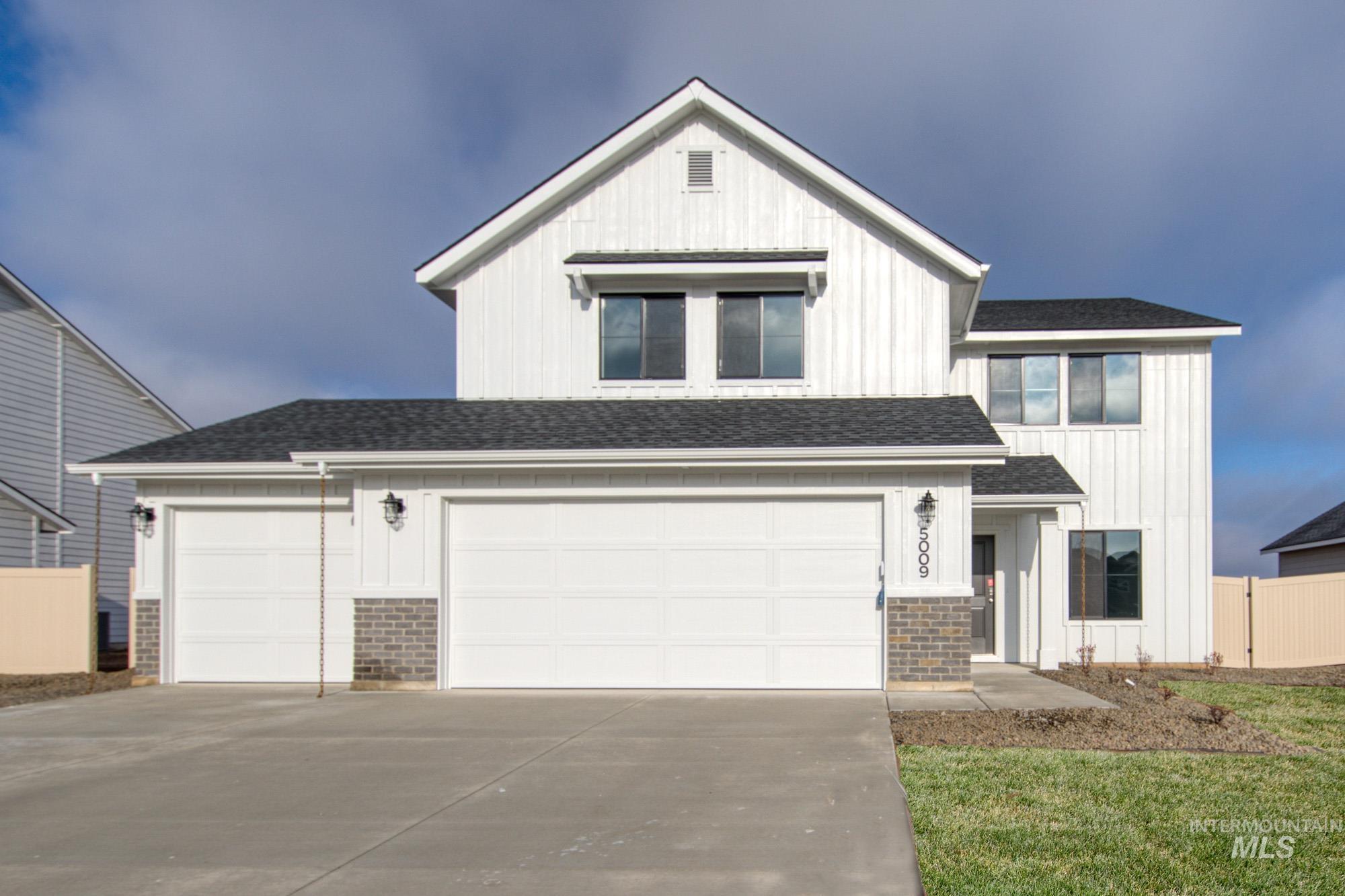 View of front of home with board and batten siding, driveway, and roof with shingles