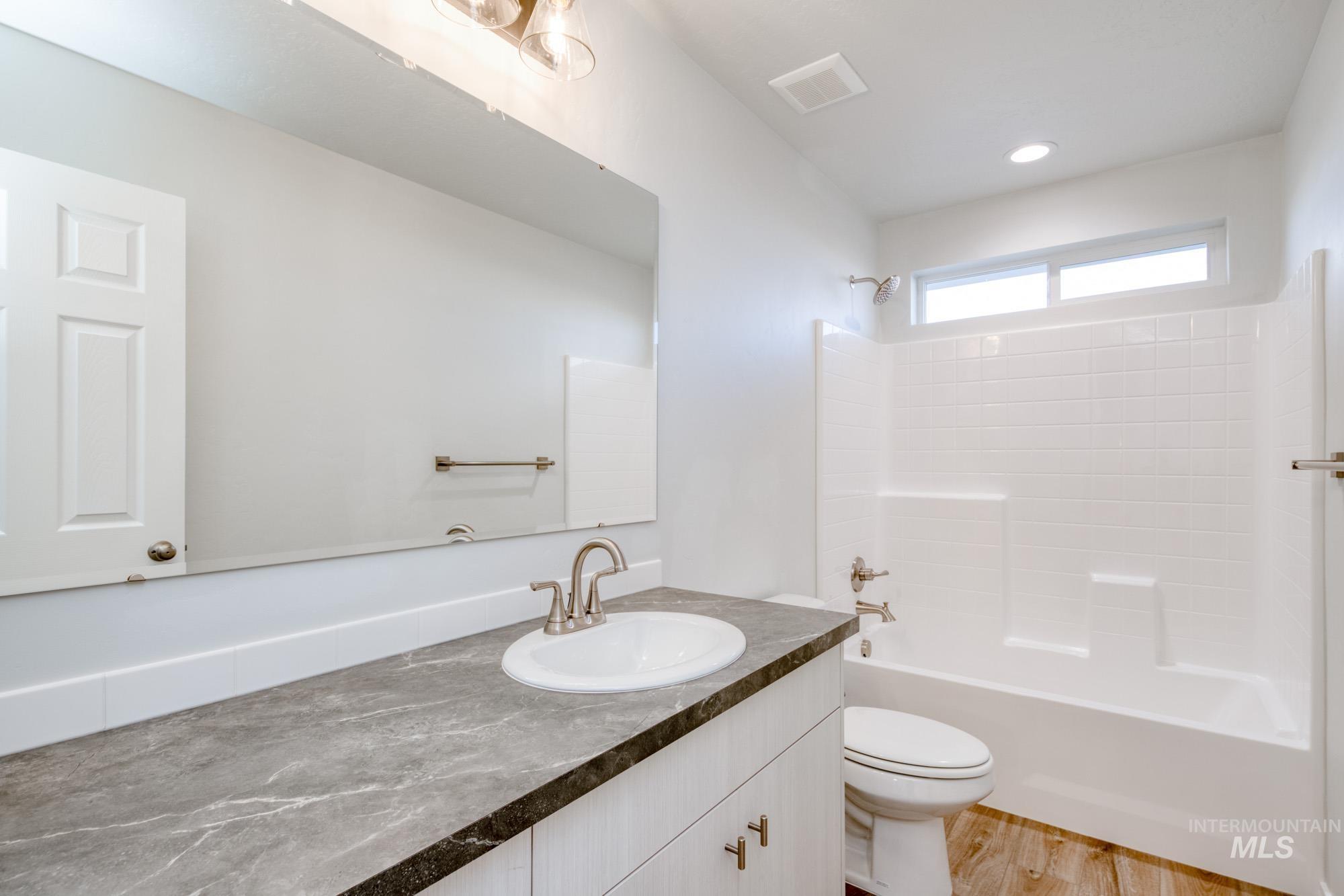 Bathroom featuring washtub / shower combination, vanity, and light wood-style flooring