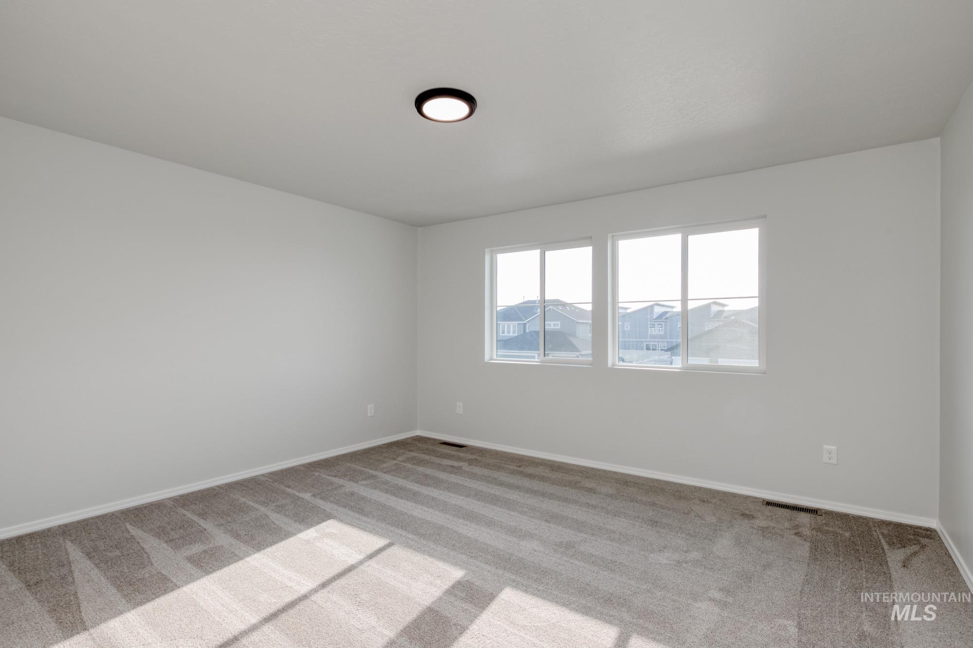 Carpeted spare room featuring baseboards
