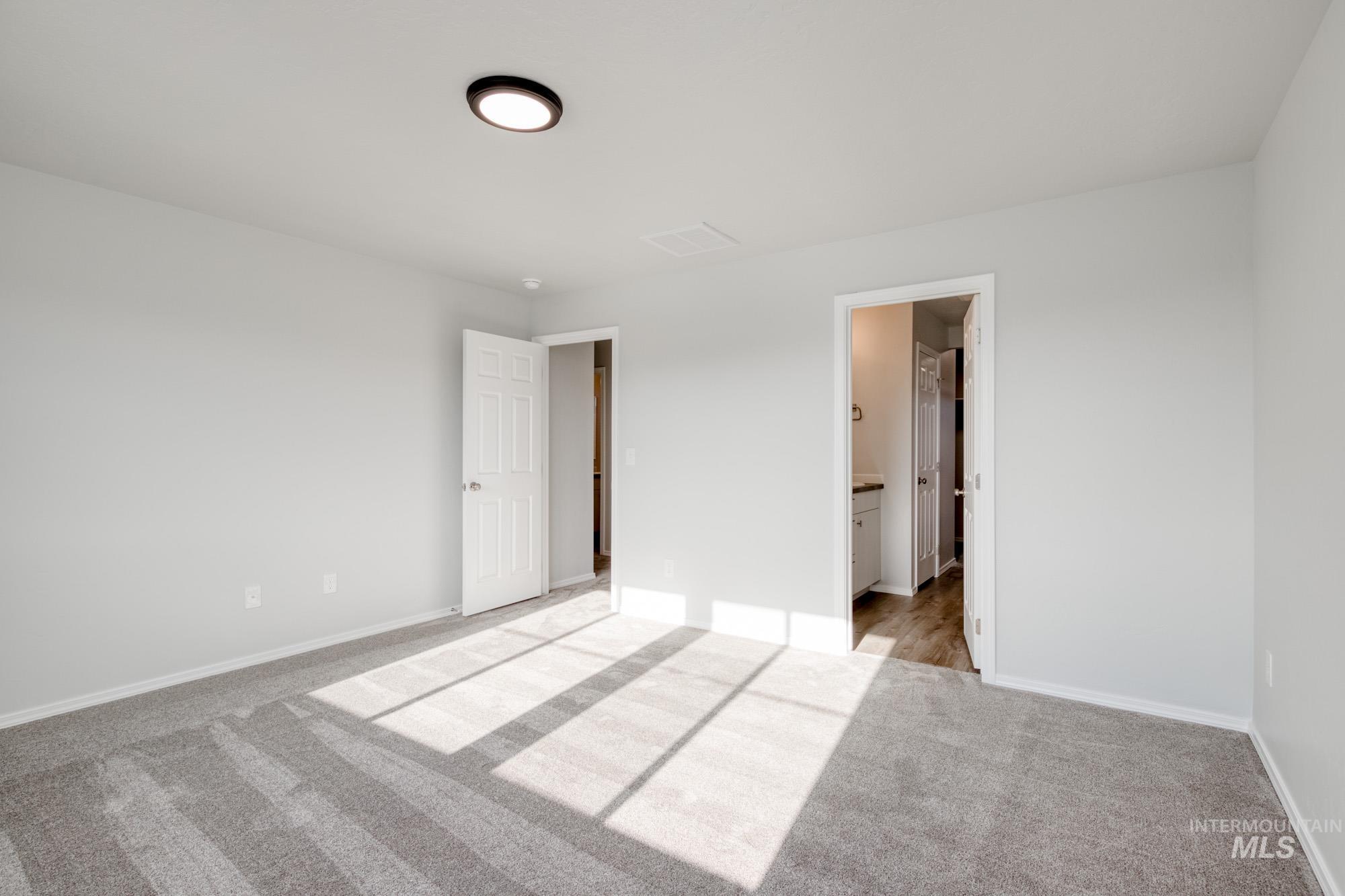 Unfurnished bedroom with light carpet and ensuite bath