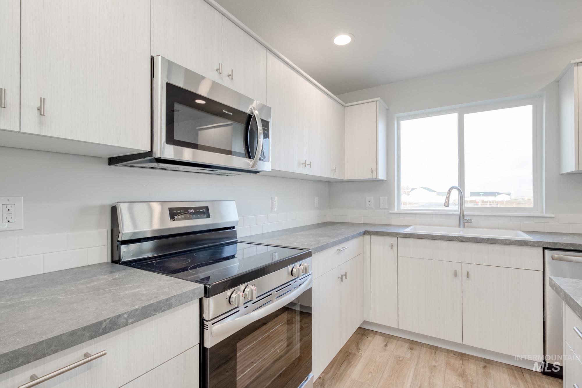 Kitchen featuring appliances with stainless steel finishes, light wood-style floors, white cabinetry, and recessed lighting