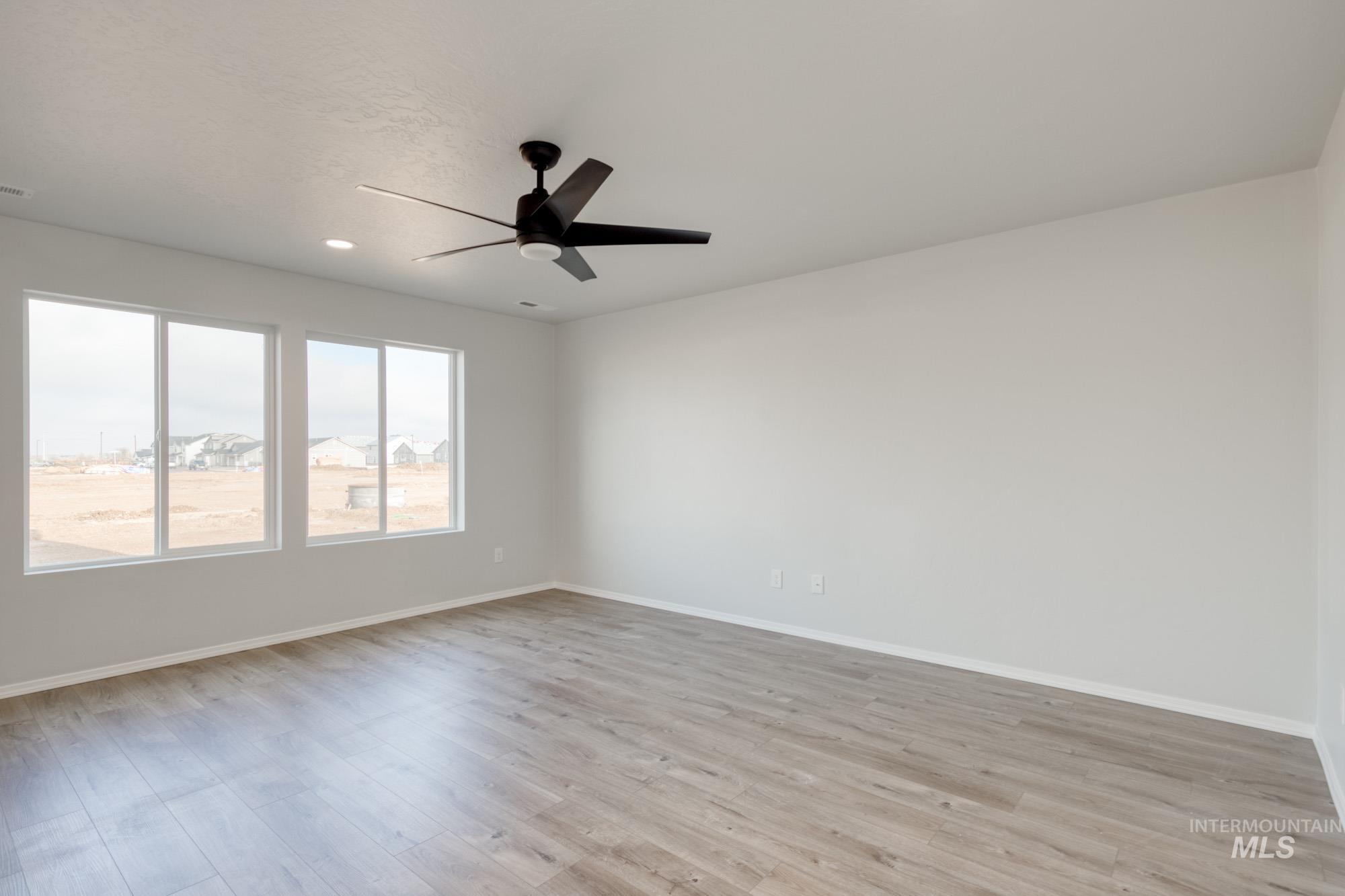 Empty room featuring light wood-style flooring, ceiling fan, and recessed lighting