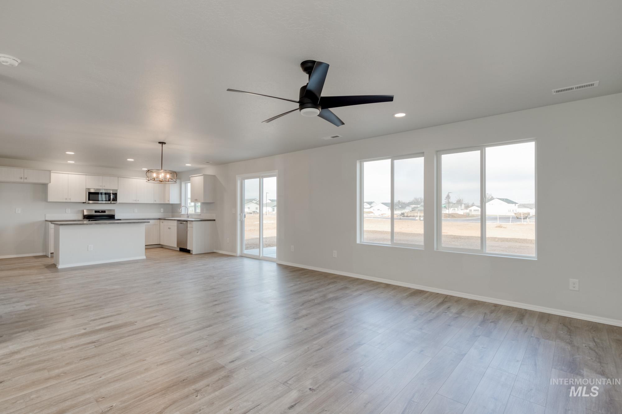 Unfurnished living room featuring recessed lighting, a chandelier, light wood-style flooring, and a ceiling fan