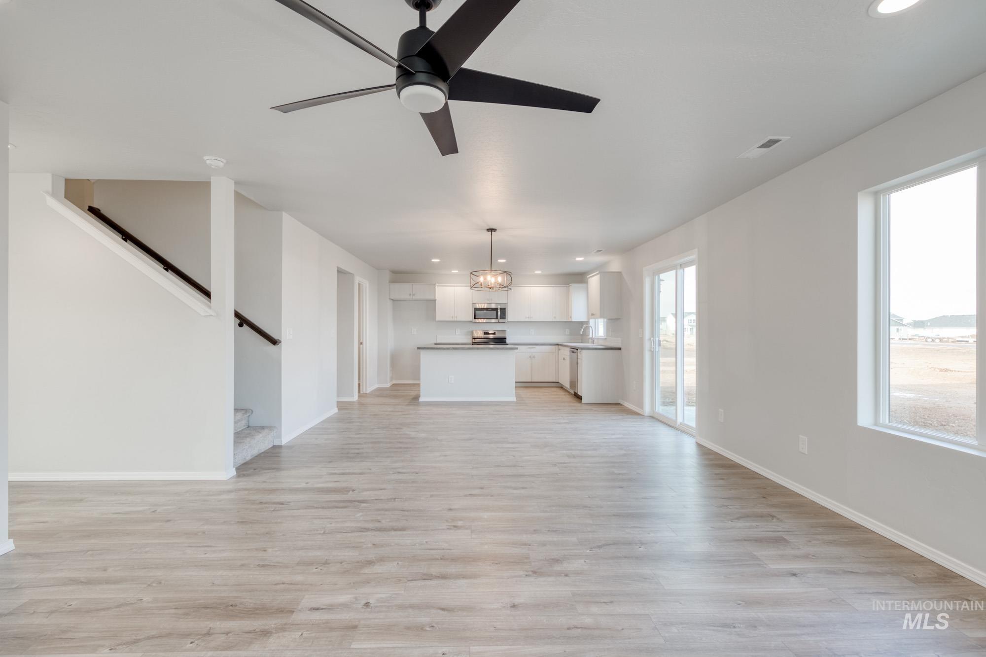 Unfurnished living room featuring recessed lighting, ceiling fan, light wood-type flooring, and stairway