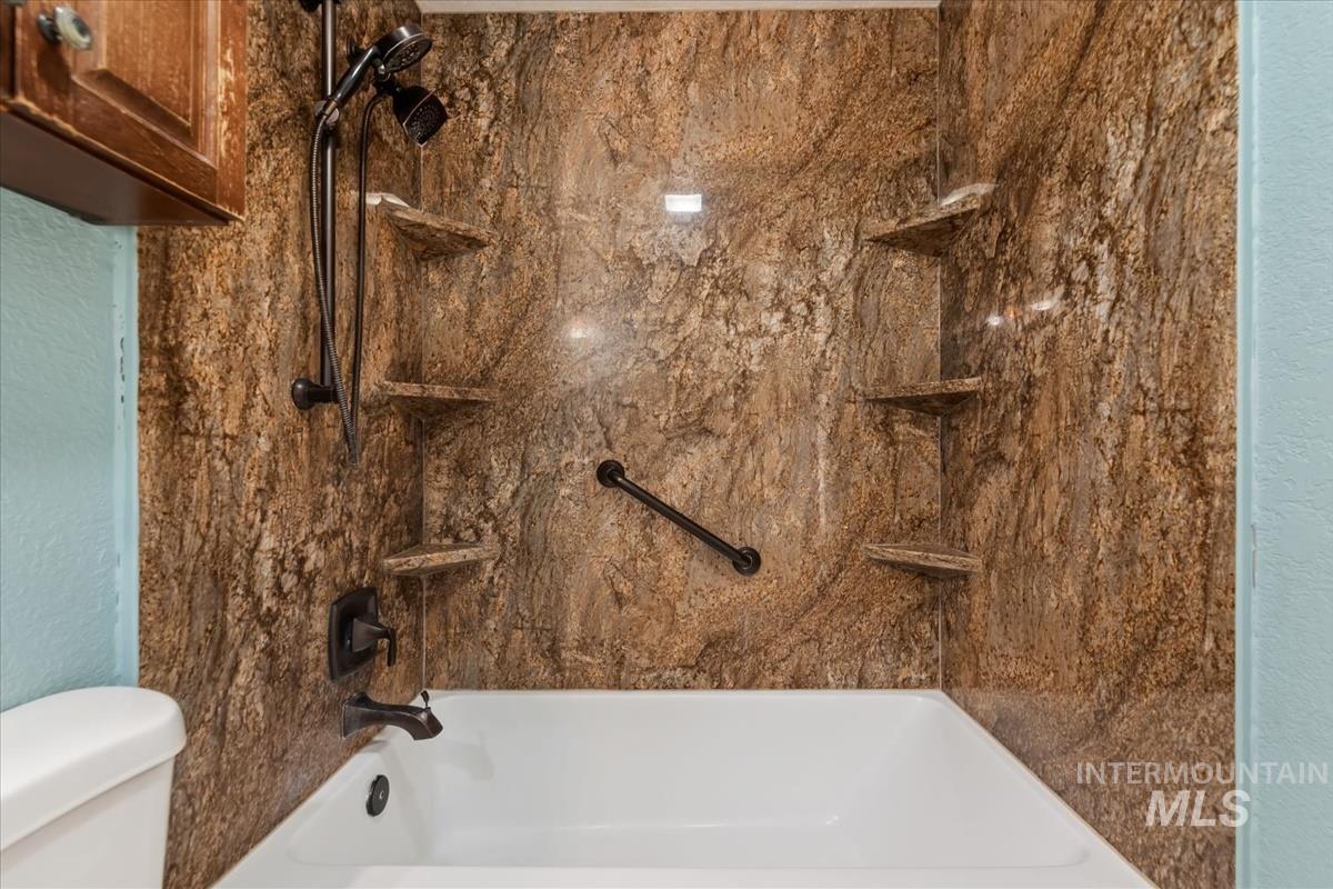 Full bath featuring bathing tub / shower combination and a textured wall