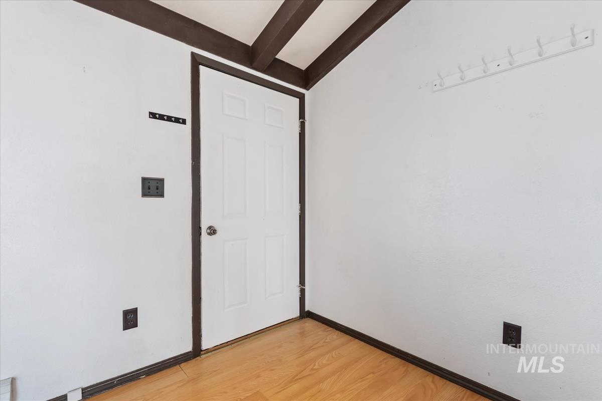 Unfurnished room with light wood-style floors and beam ceiling