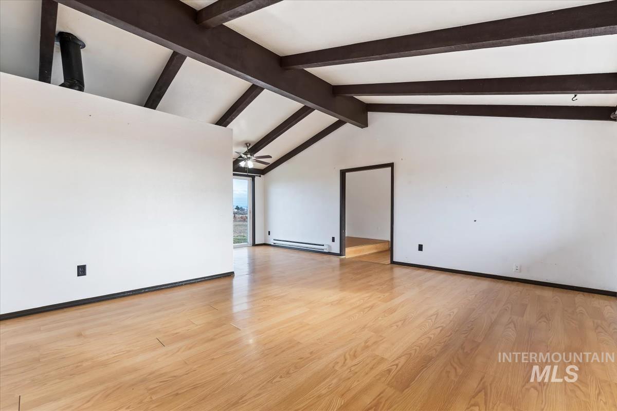 Unfurnished living room featuring light wood finished floors, a baseboard radiator, and a ceiling fan