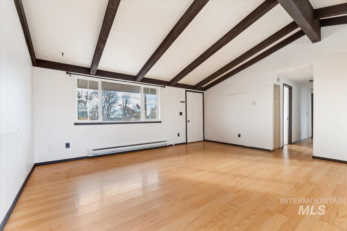 Unfurnished living room featuring baseboard heating and light wood-style flooring