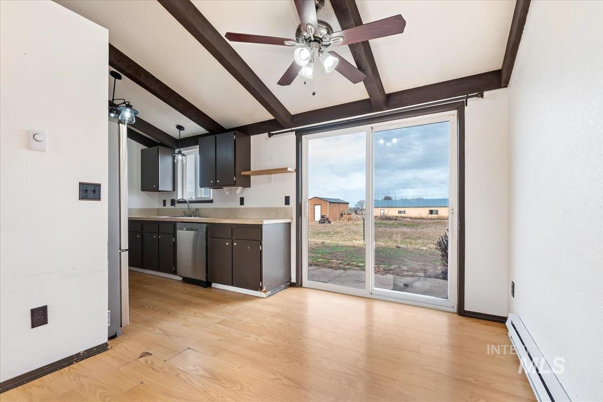 Kitchen with a baseboard radiator, light countertops, light wood-style flooring, a ceiling fan, and stainless steel appliances
