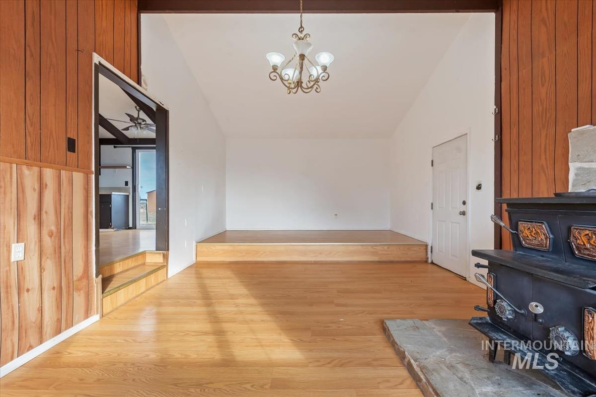 Entrance foyer featuring a wood stove, light wood finished floors, lofted ceiling, a chandelier, and a ceiling fan